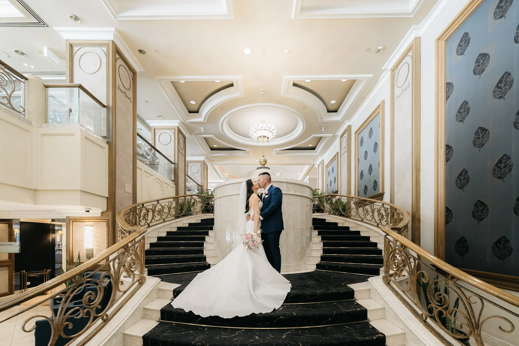 Che and Rob framed by the sweeping staircase at The Langham