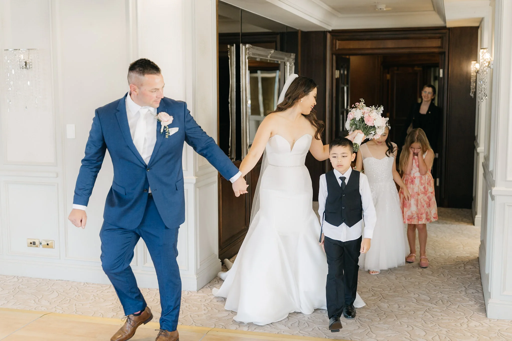 Che and Rob entering the reception hand in hand with young attendants