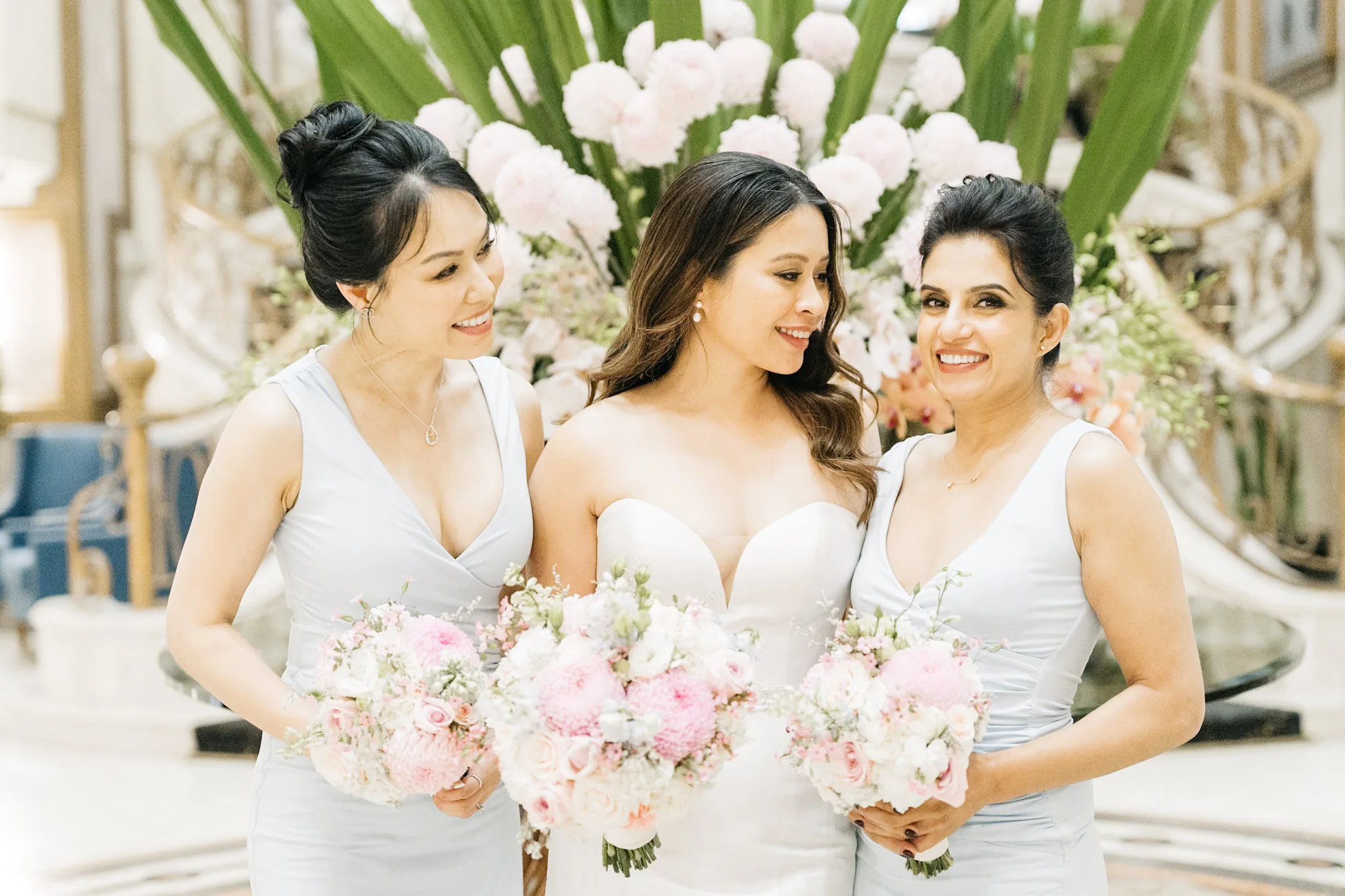 Che and her bridesmaids laughing together beside a floral arrangement