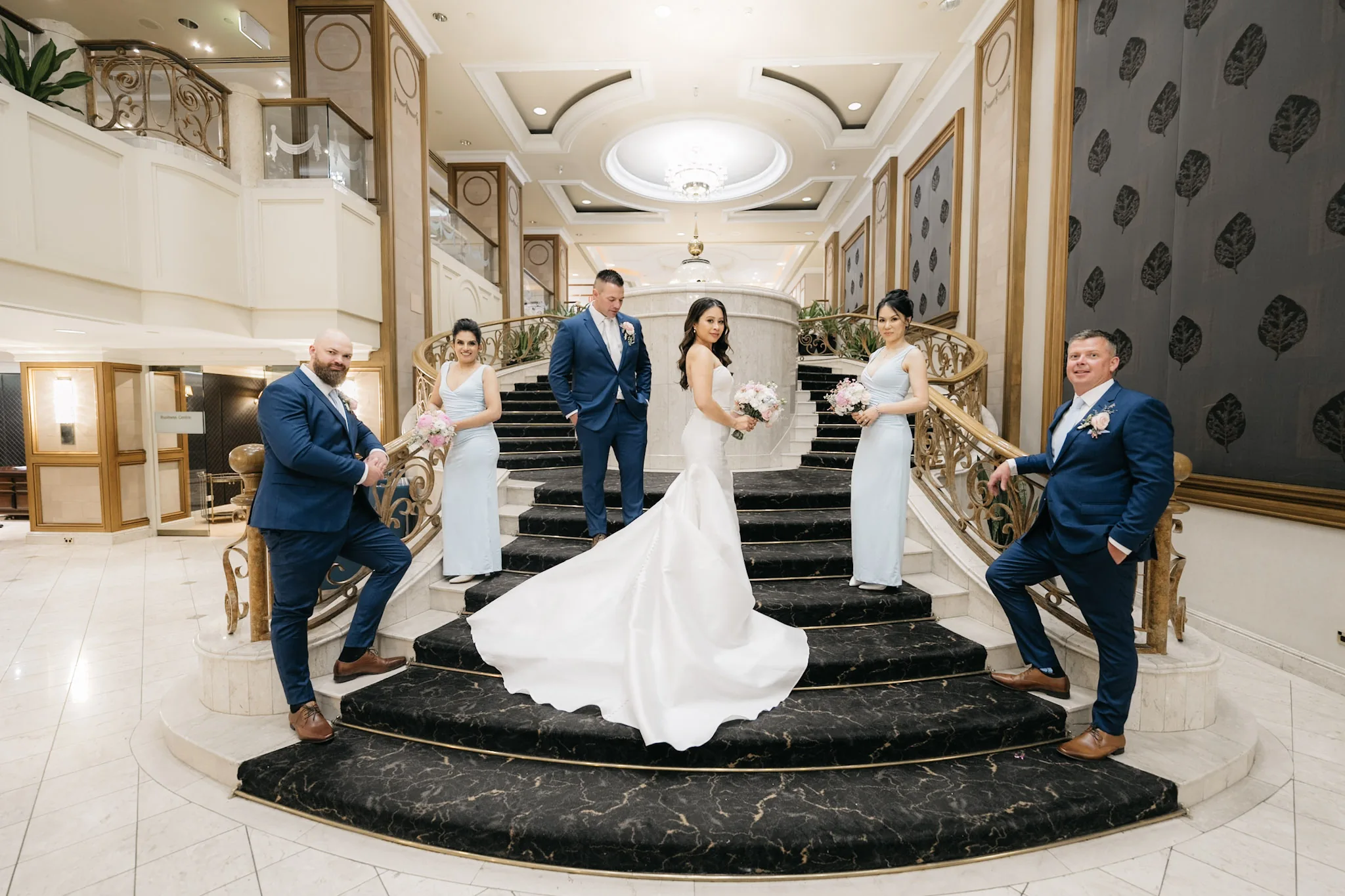 The bridal party striking playful poses across the grand staircase
