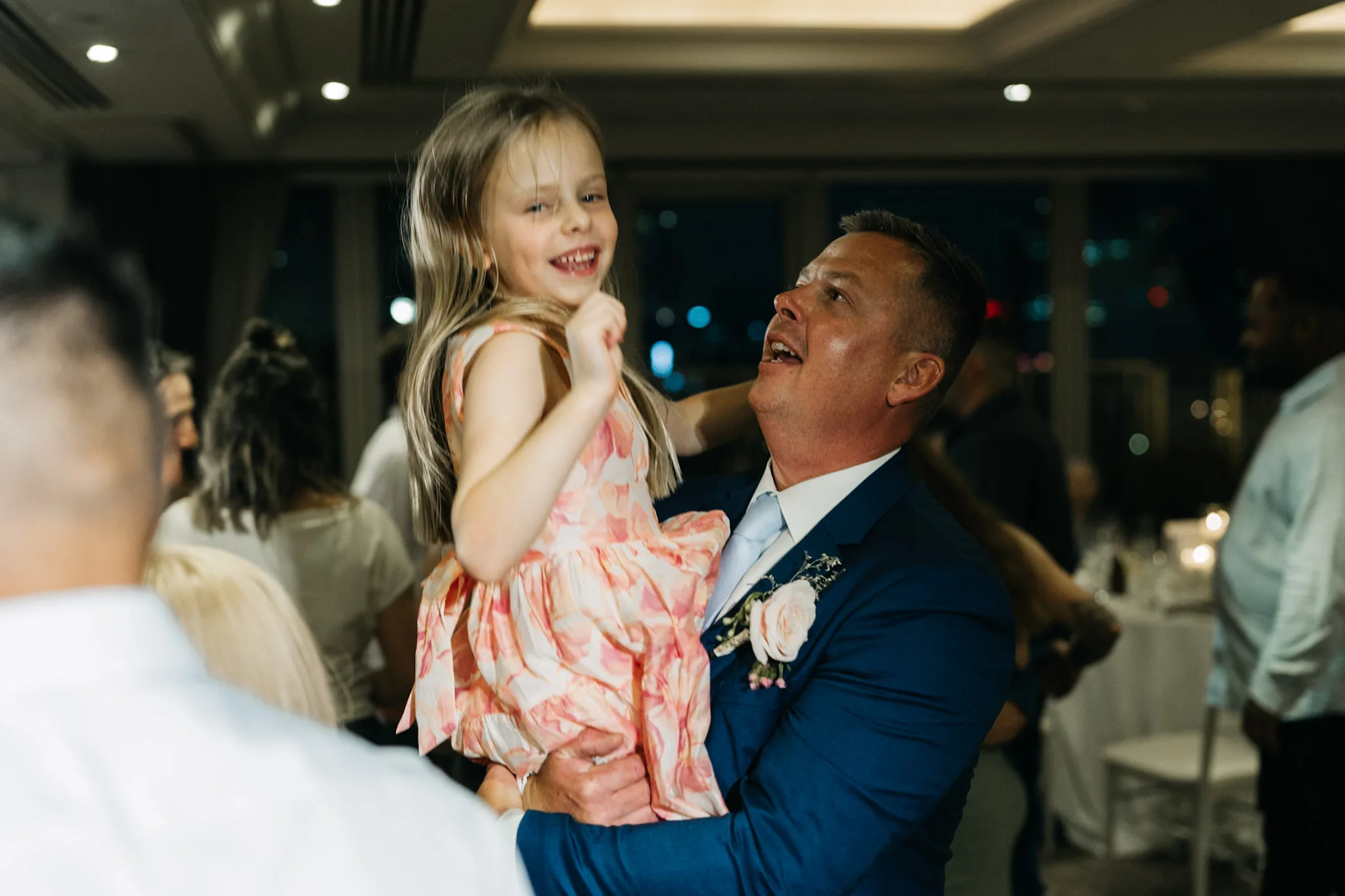 A guest holding a smiling child above the crowded dance floor