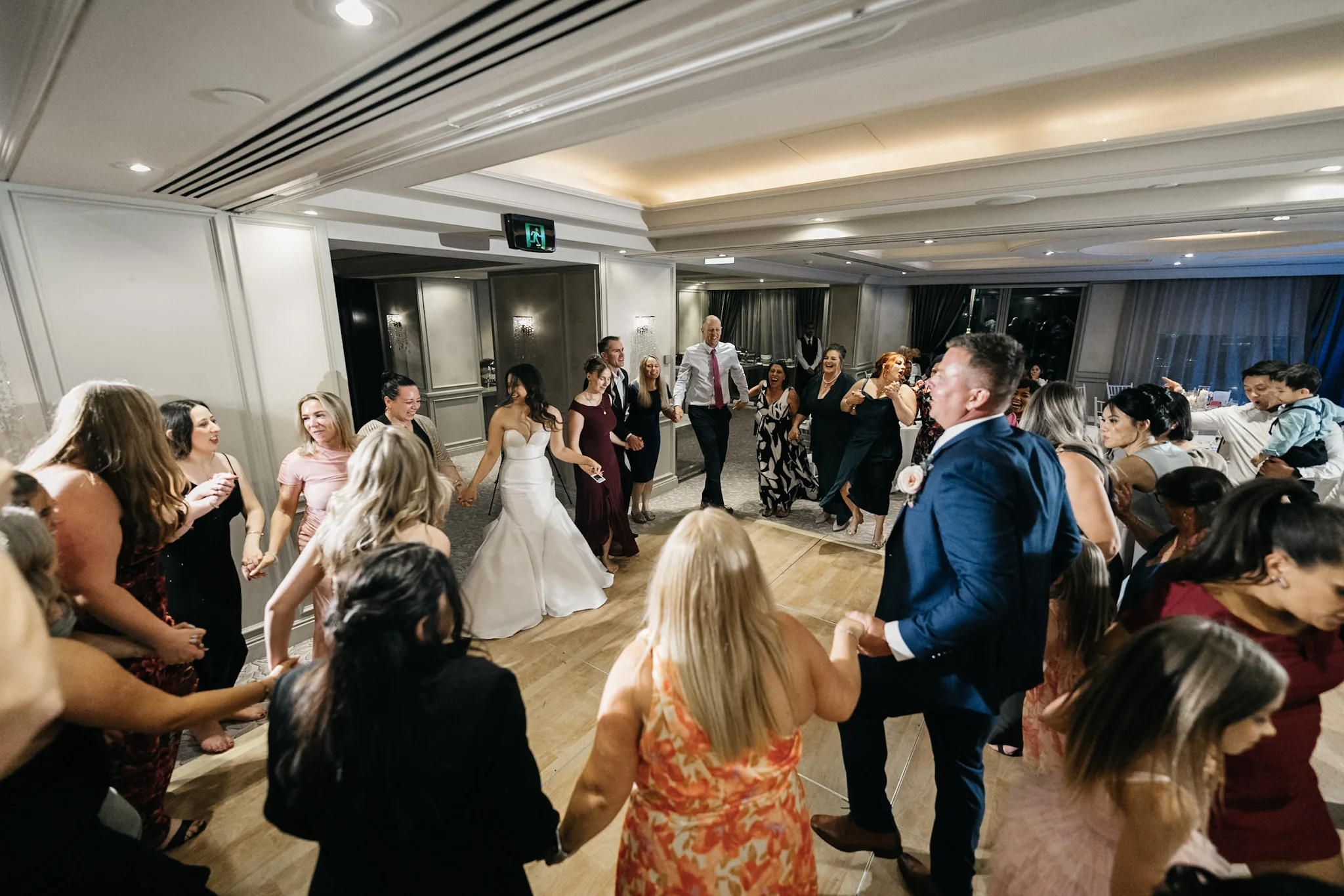 Family and friends filling the dance floor around Che and Rob