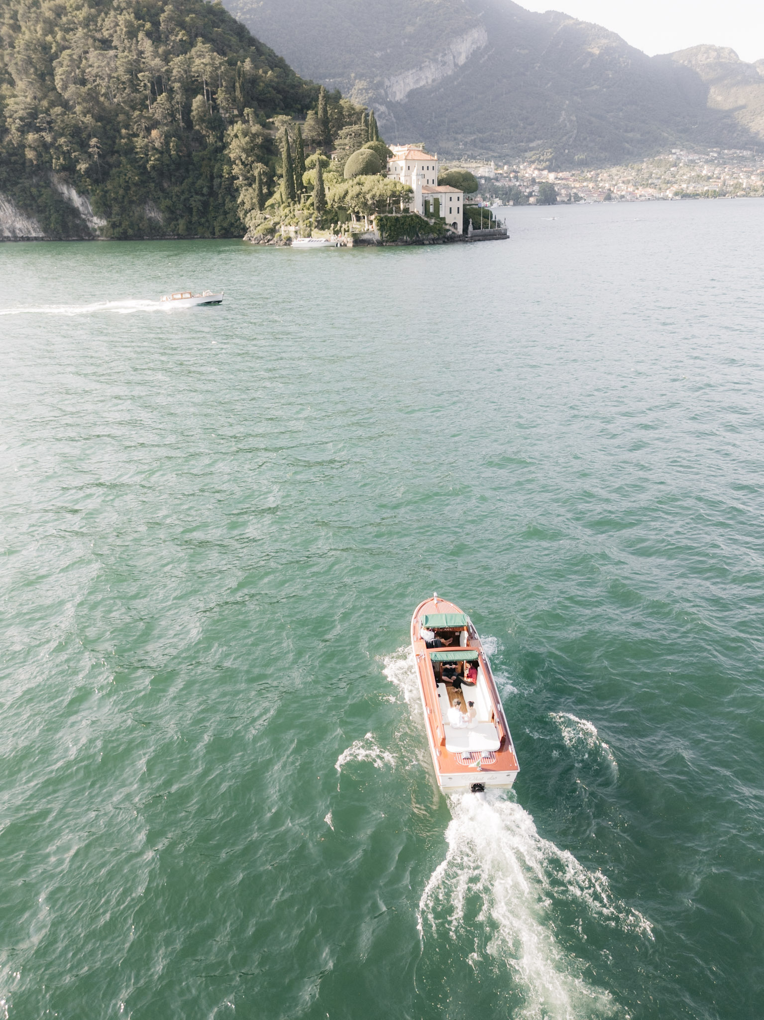 The boat opening a bright wake across Lake Como