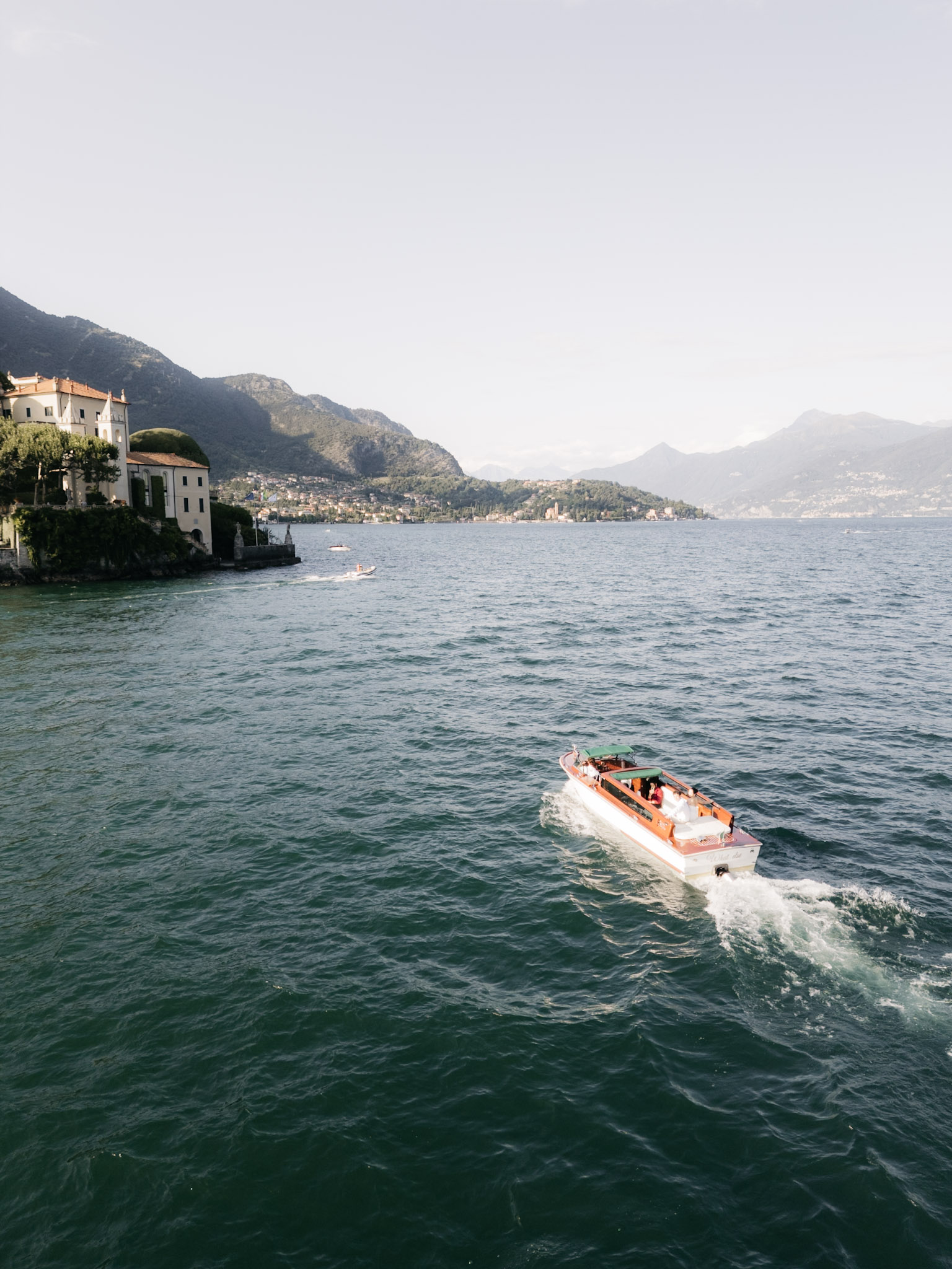 A wide view of the boat passing the villas along Lake Como
