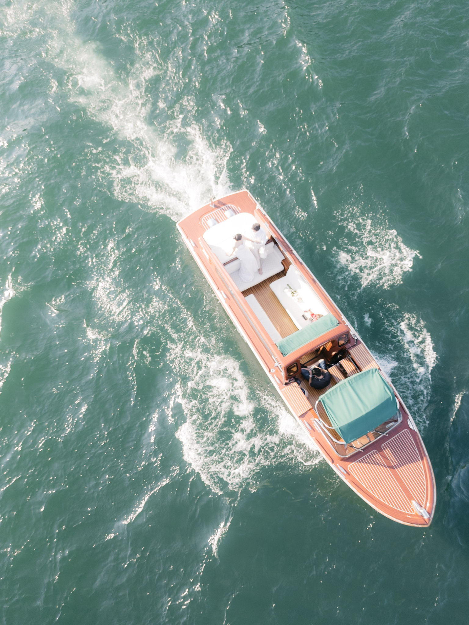 The boat seen directly overhead, wake fanning behind it