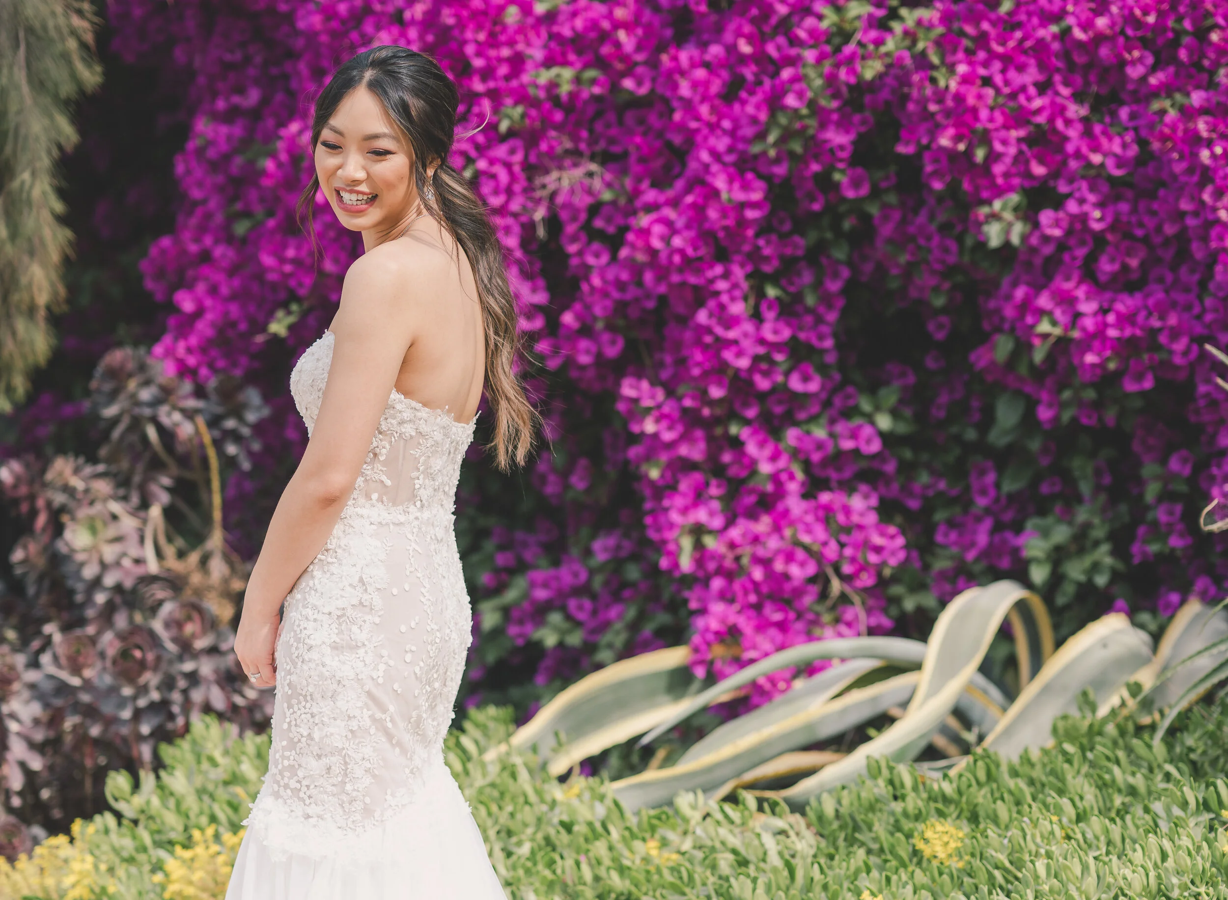 Bride smiling beside vivid magenta bougainvillea
