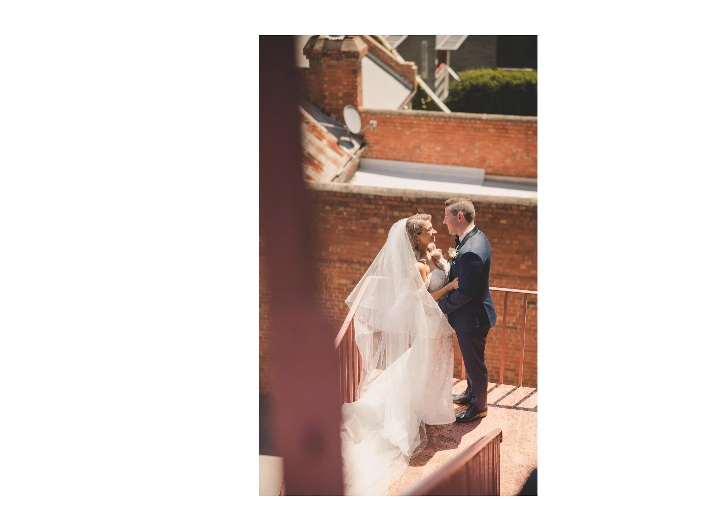 Newlyweds embracing on a sunlit brick staircase