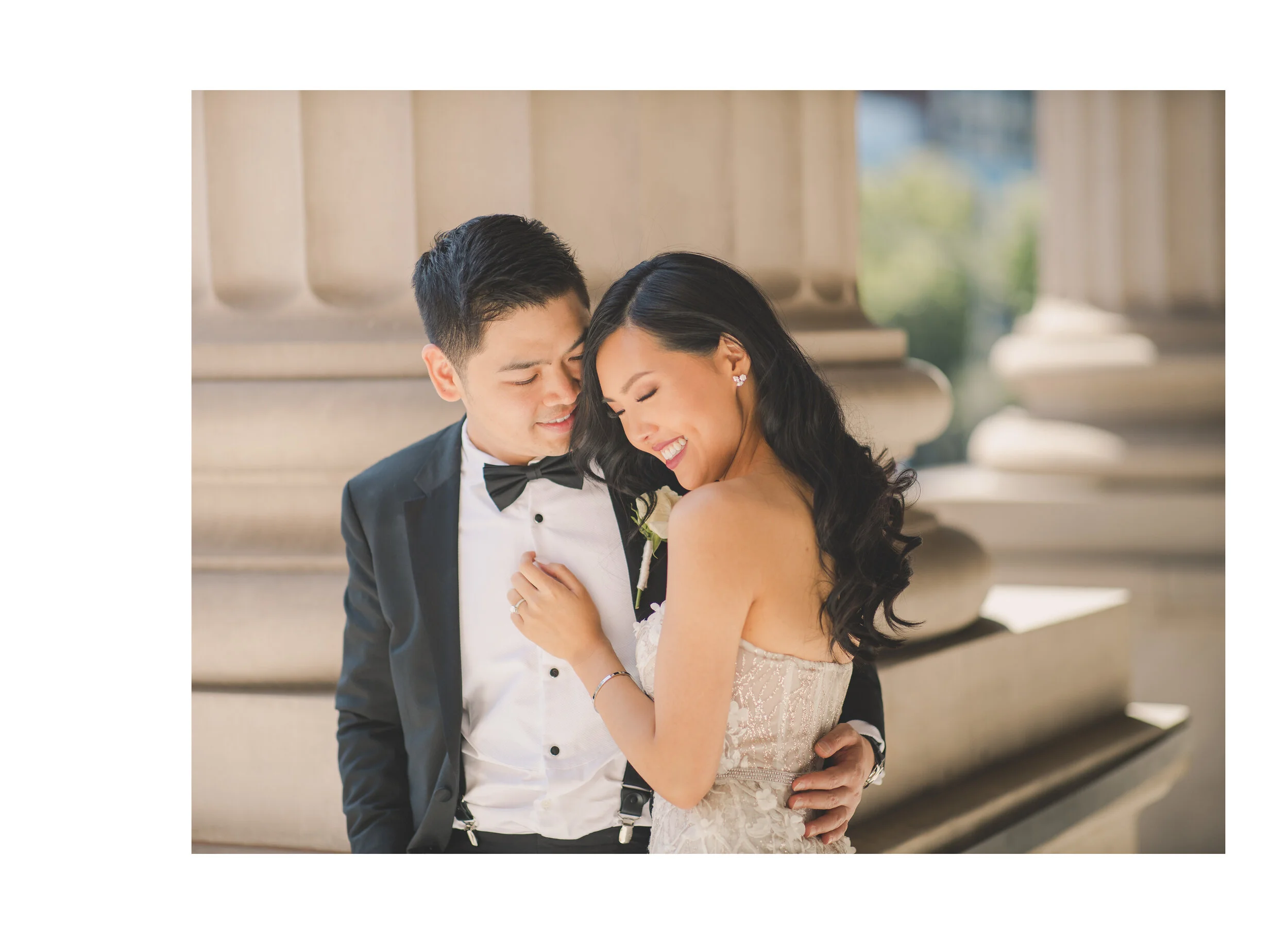 Newlyweds sharing a laugh beside sandstone columns