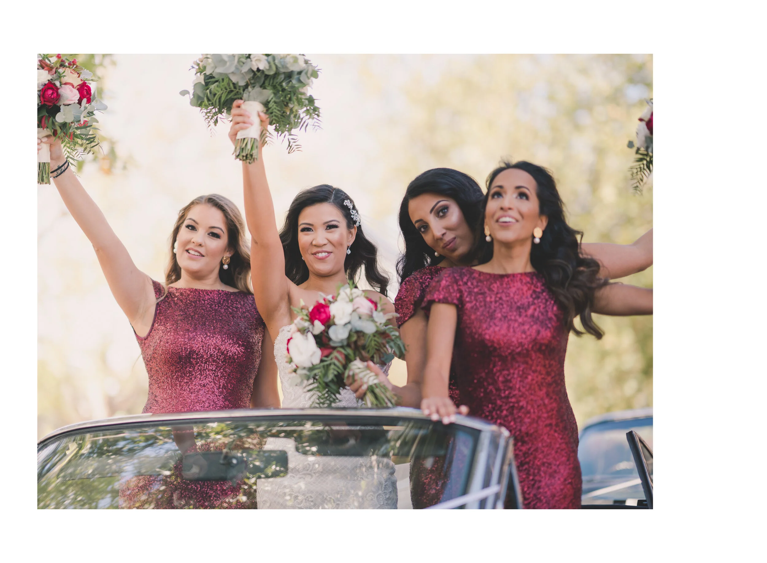 Bride and bridesmaids cheering from a convertible