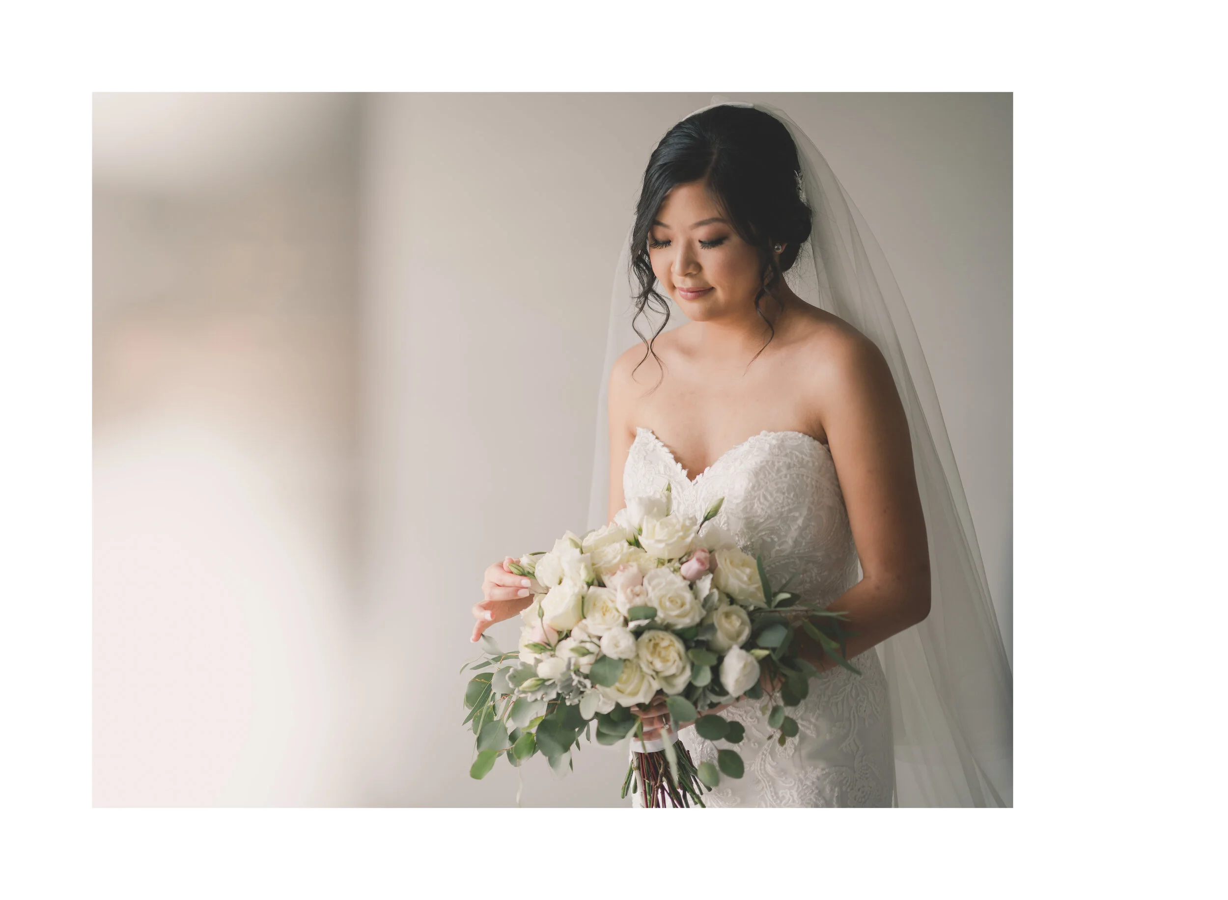 Bride holding a white bouquet in soft window light