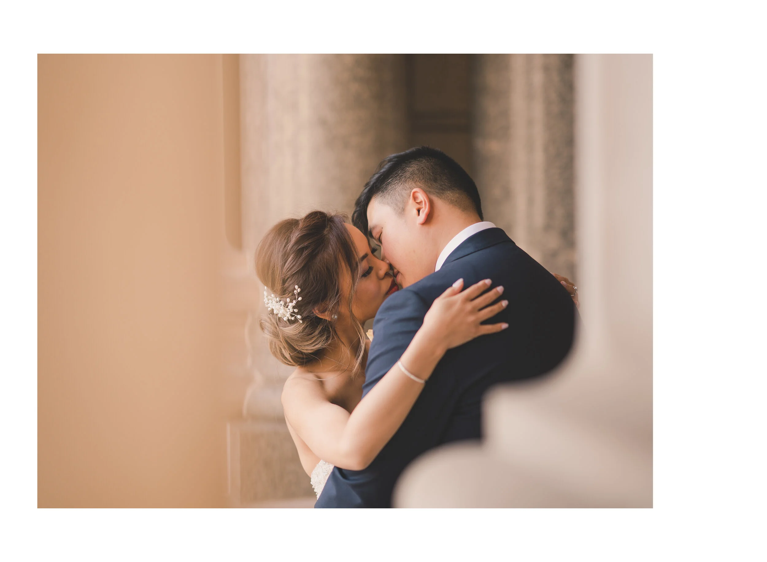 Newlyweds kissing against warm sandstone architecture