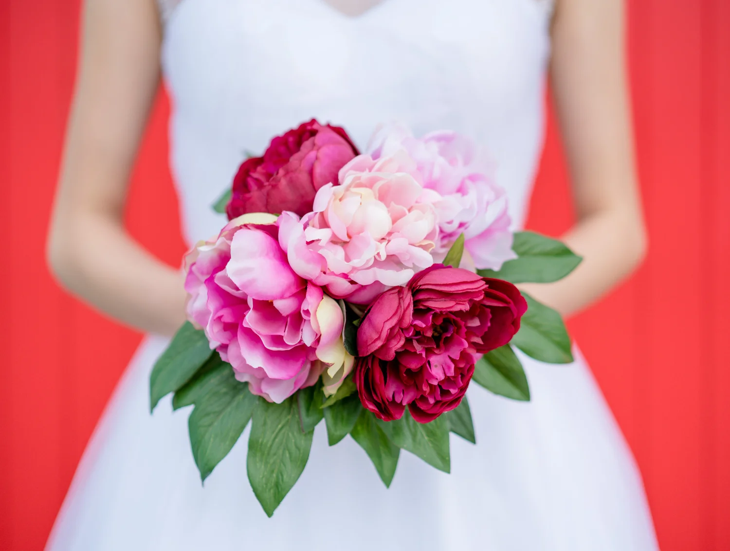 Bright pink wedding bouquet against a red dress