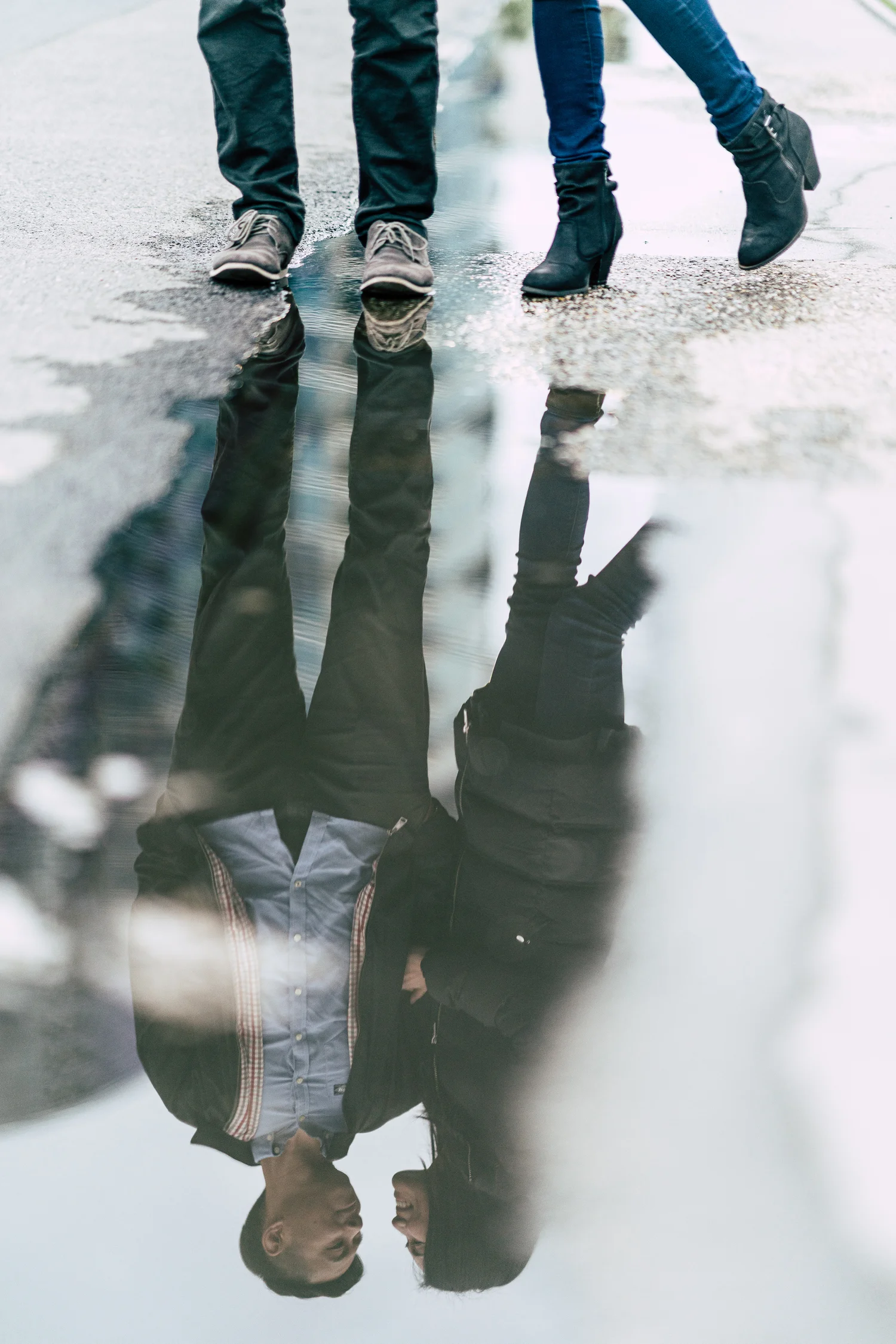 Newlyweds reflected in rainwater on a city street