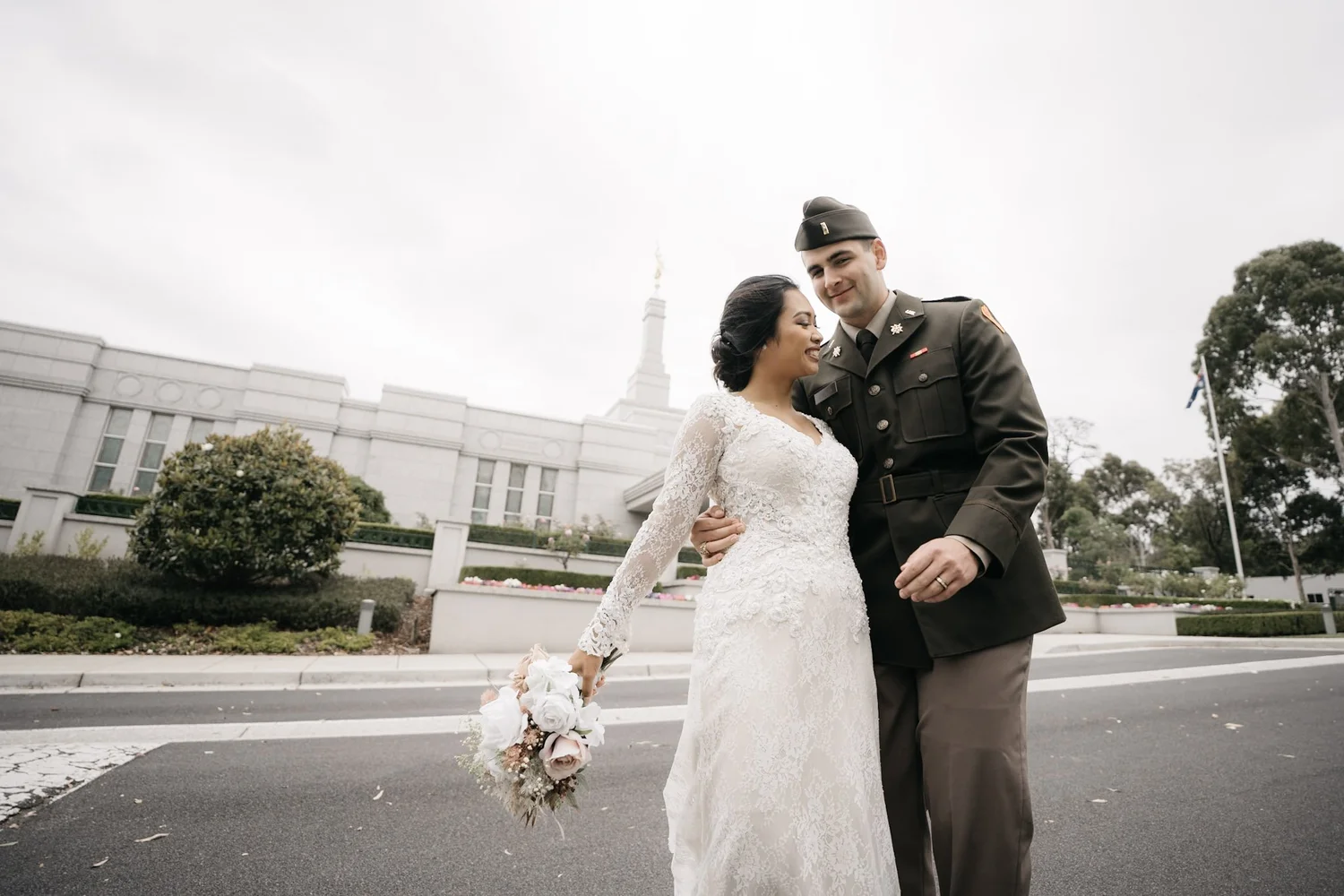 Newlyweds laughing together beside a quiet road