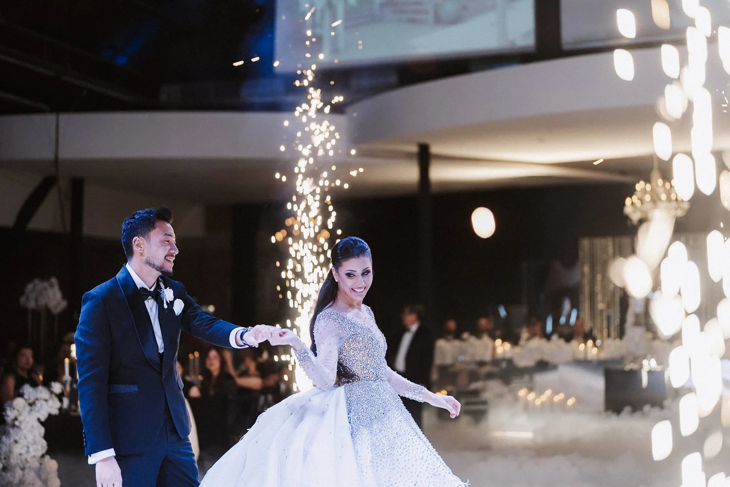 Newlyweds dancing between indoor spark fountains