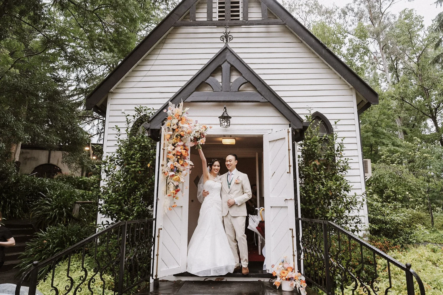 Newlyweds standing at the entrance to a timber chapel