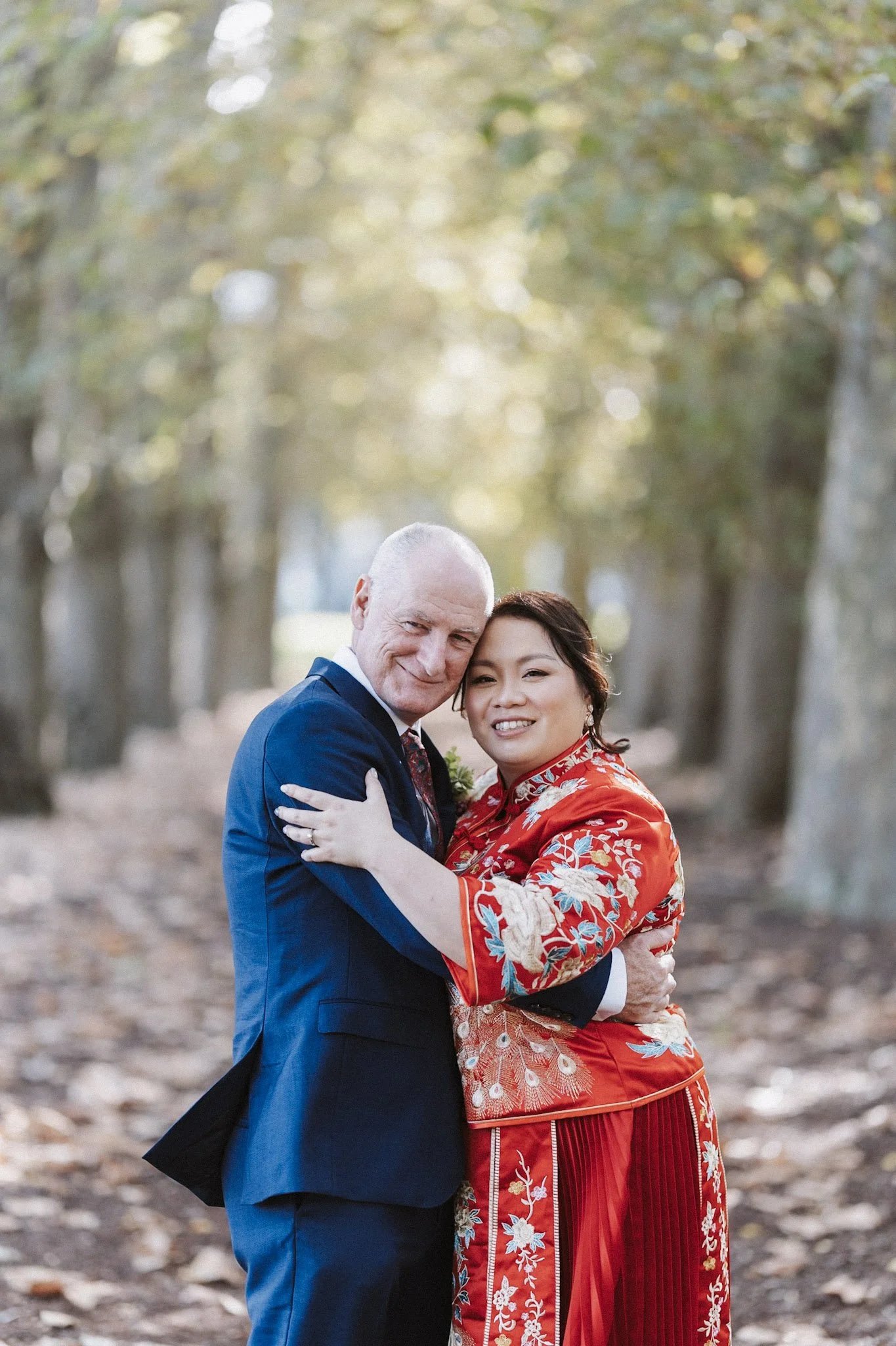 Couple in red wedding attire smiling in a forest
