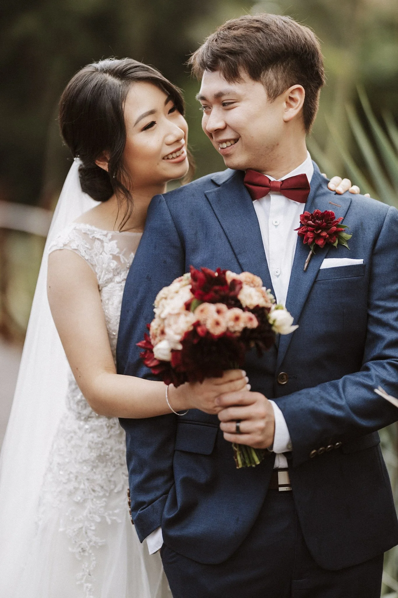 Newlyweds smiling together with a red bouquet
