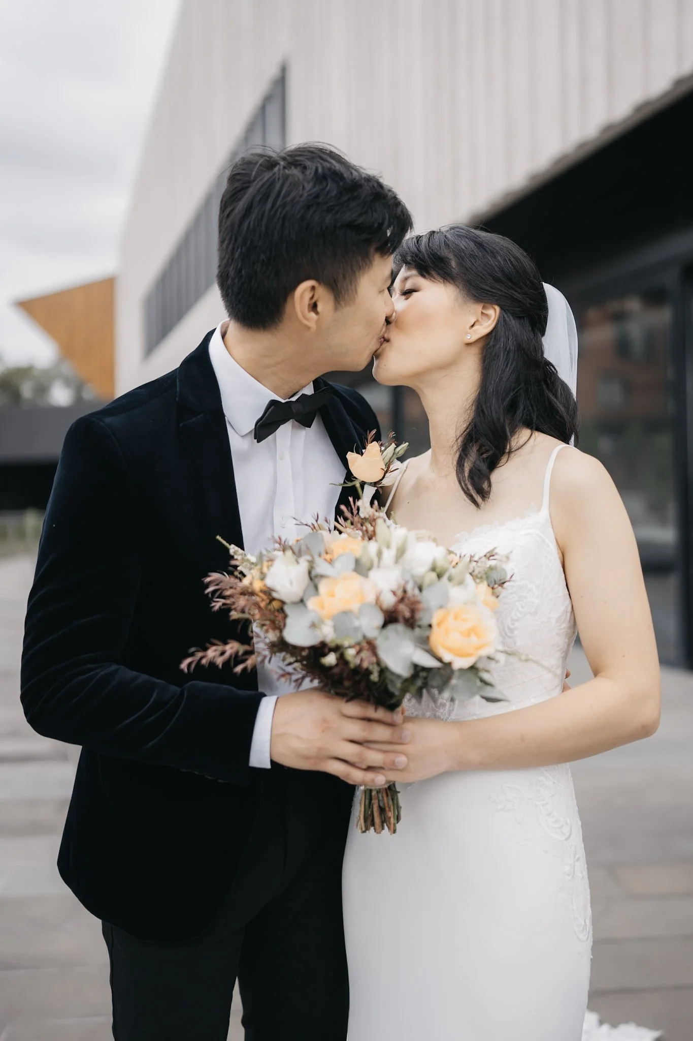 Wedding couple kissing outside a modern building