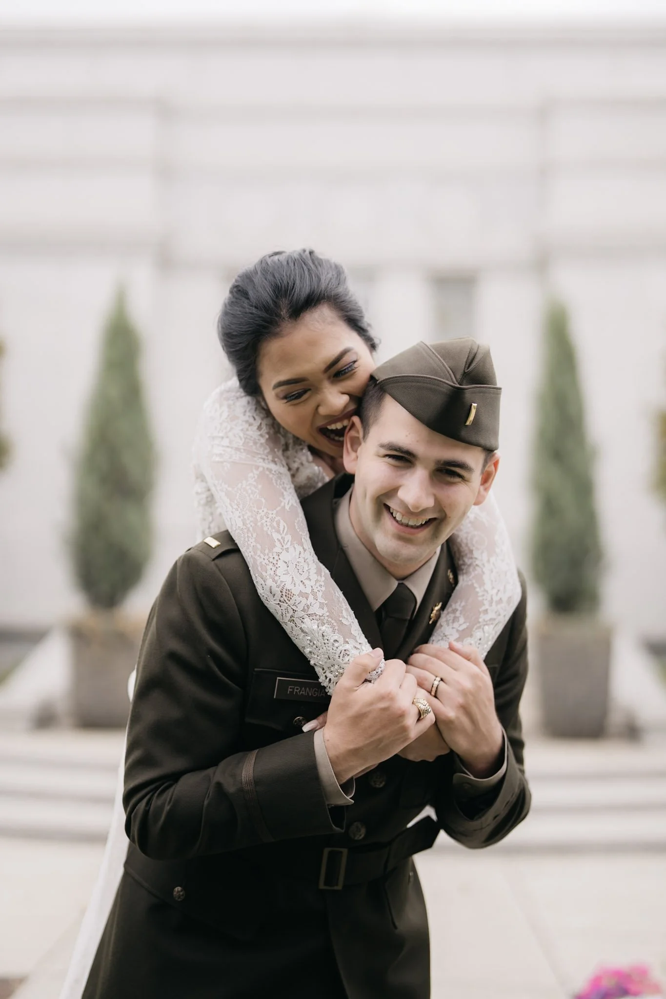 Couple laughing closely outside a white building