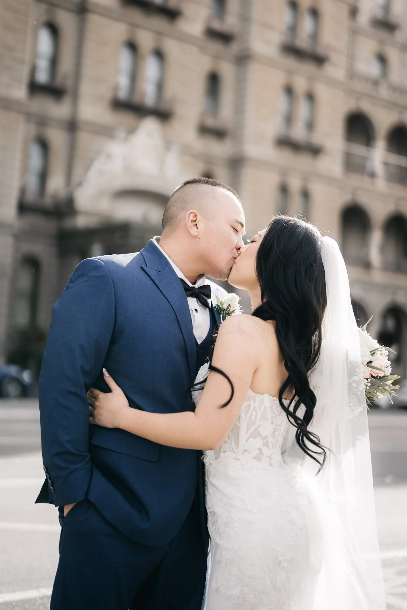 Newlyweds sharing a kiss outside a heritage building