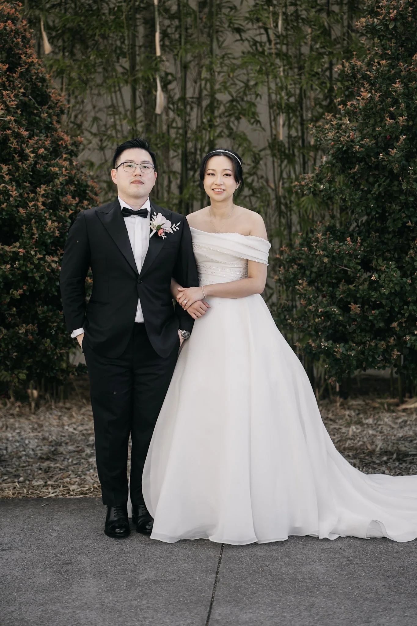 Wedding couple standing together beneath tall trees