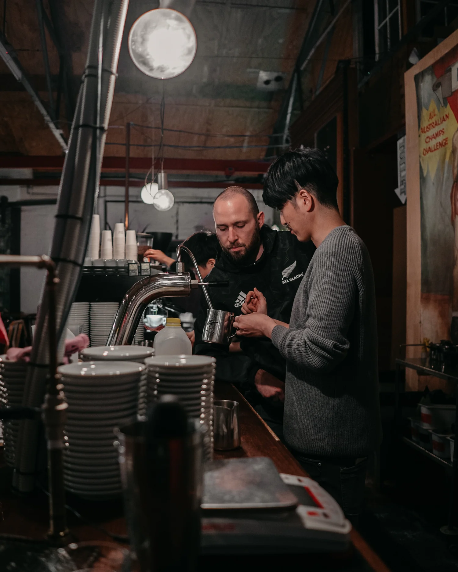 Two hospitality staff working together behind an espresso bar