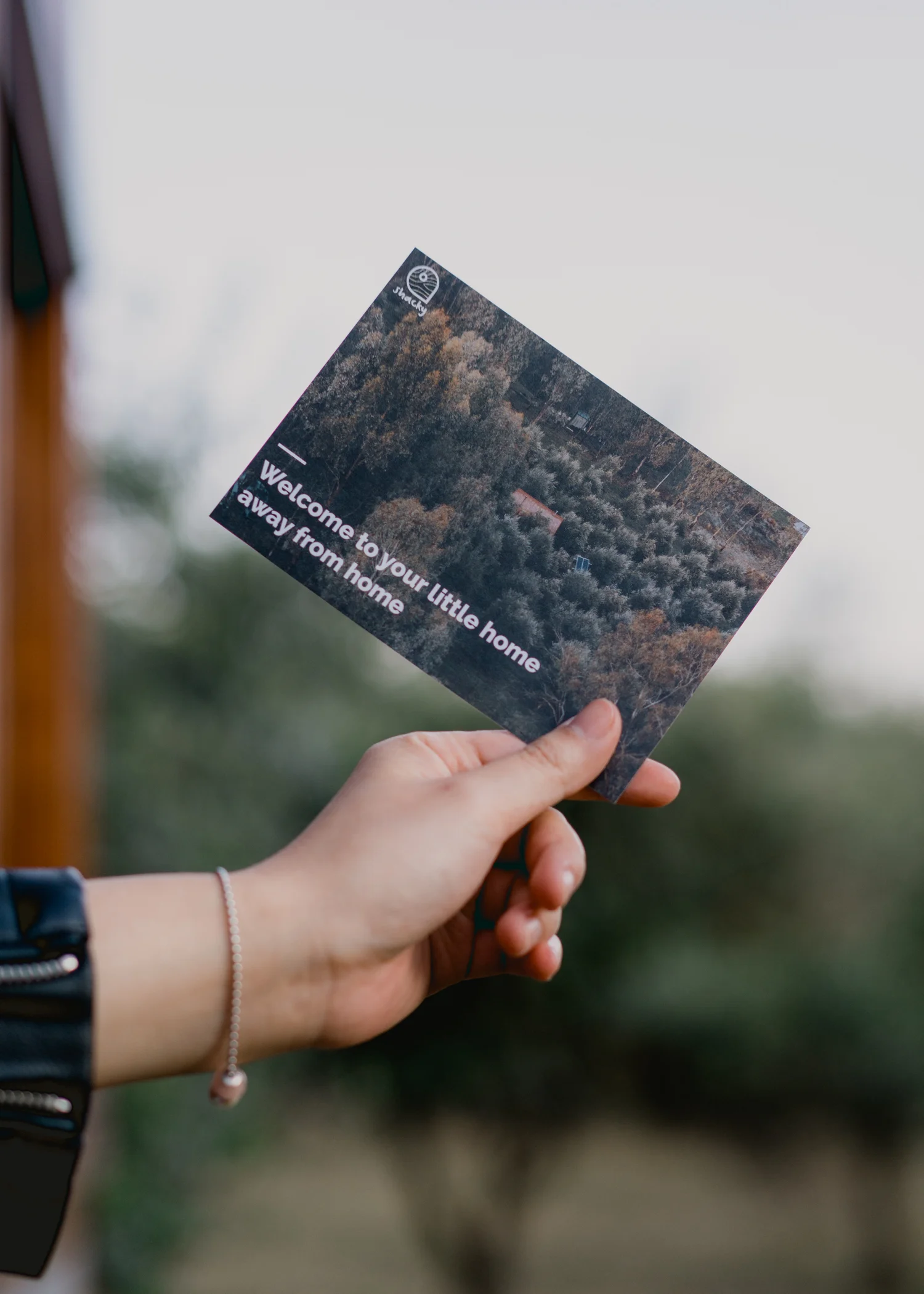 Hand holding a welcome card against a softly blurred rural backdrop