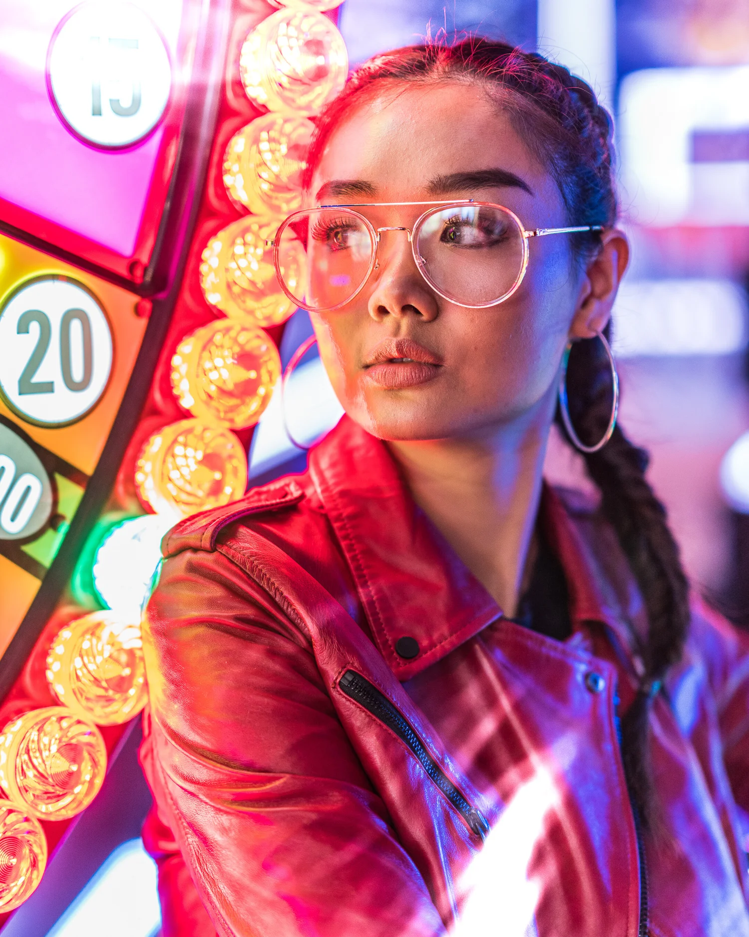 Neon-lit portrait of a woman wearing glasses in an arcade