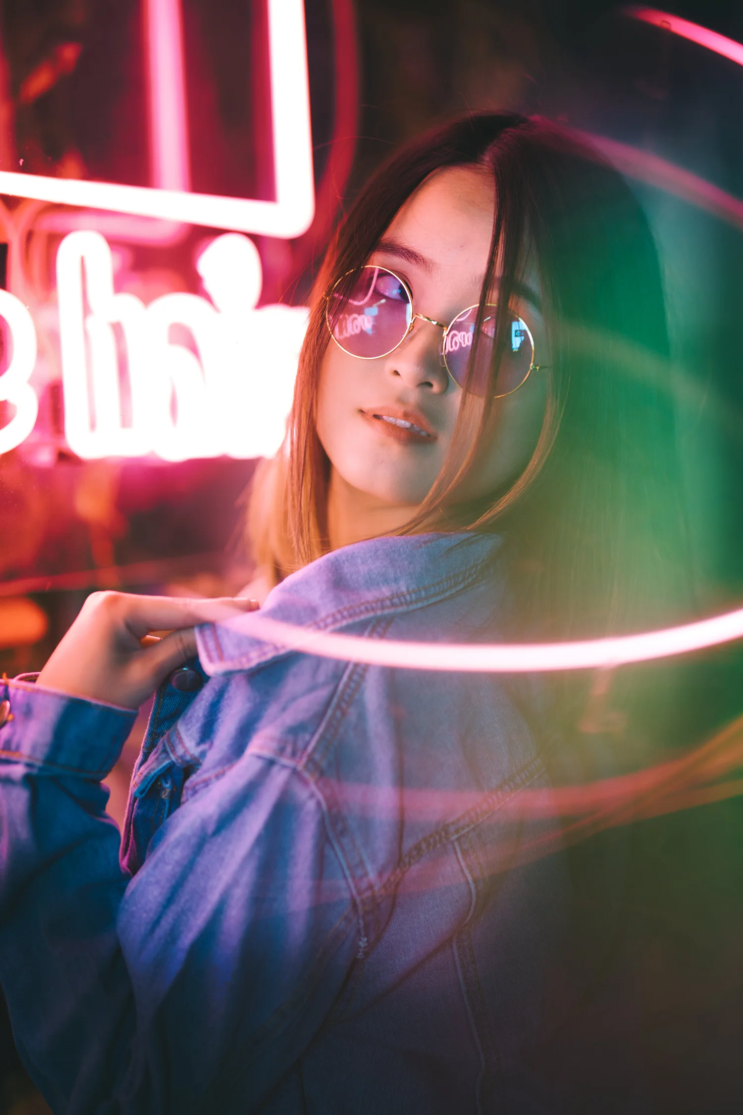 Portrait of a woman behind sweeping pink and blue neon light trails