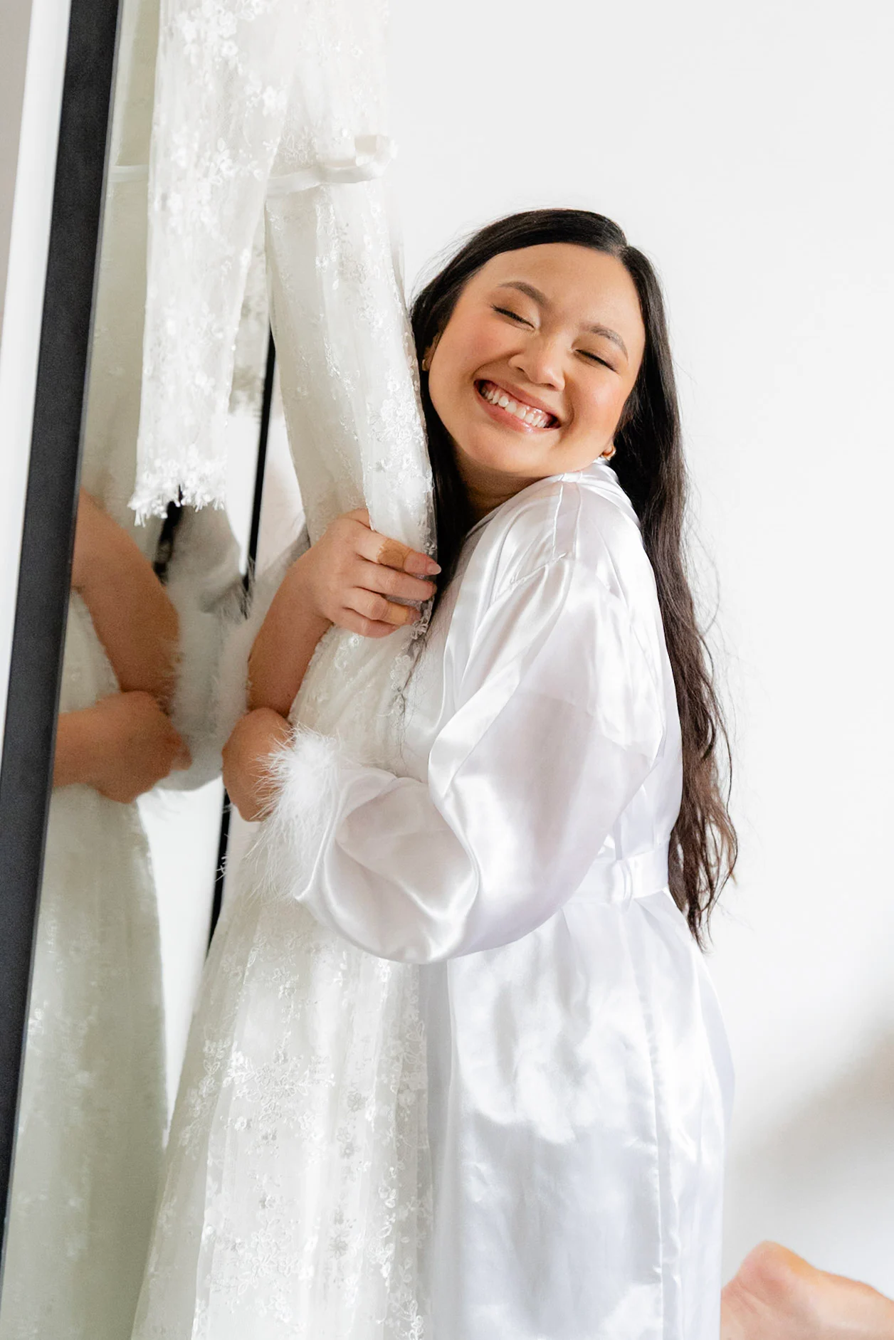 Joy smiling beside her wedding dress