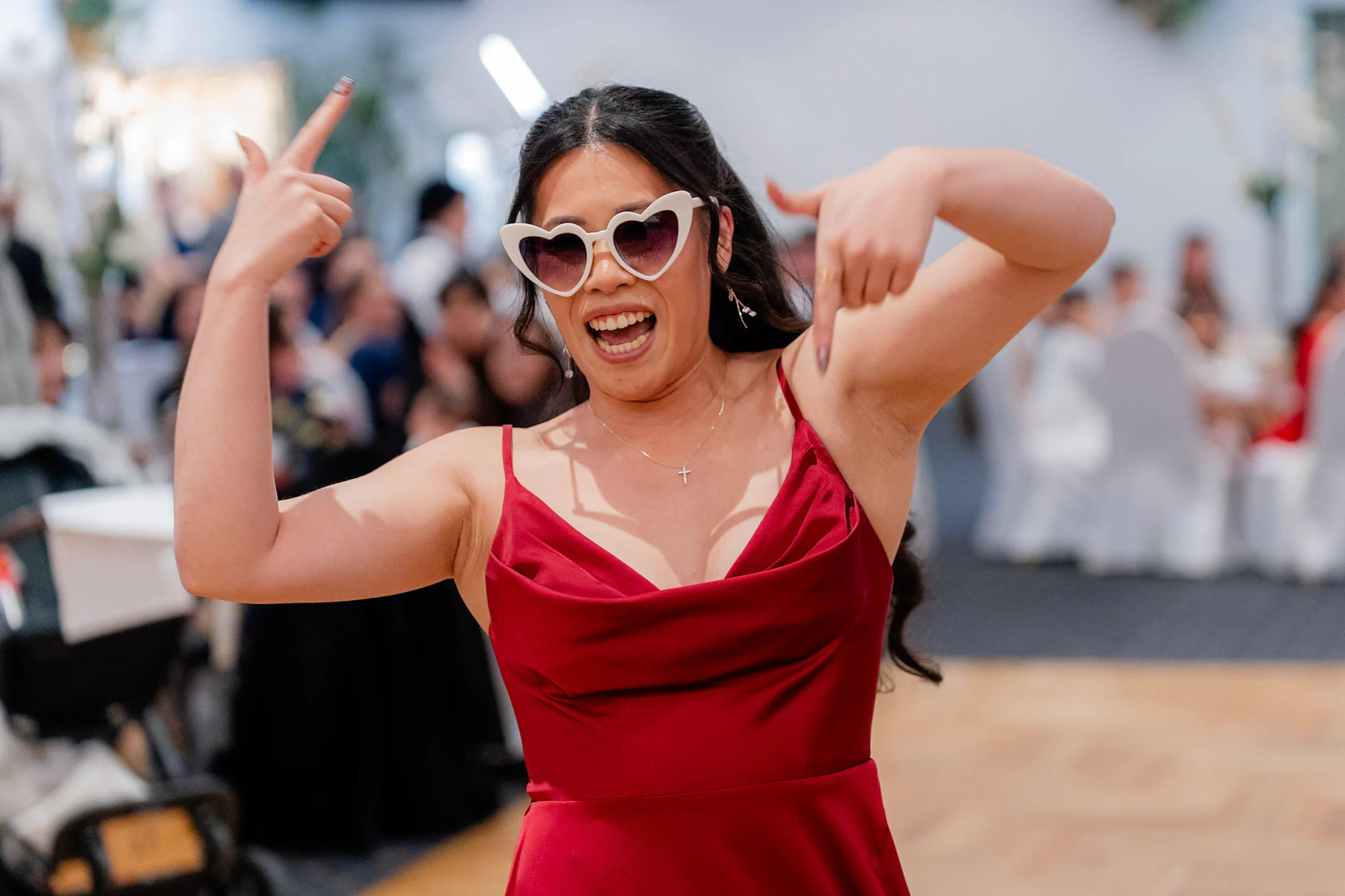 A bridesmaid making a playful reception entrance in heart-shaped sunglasses