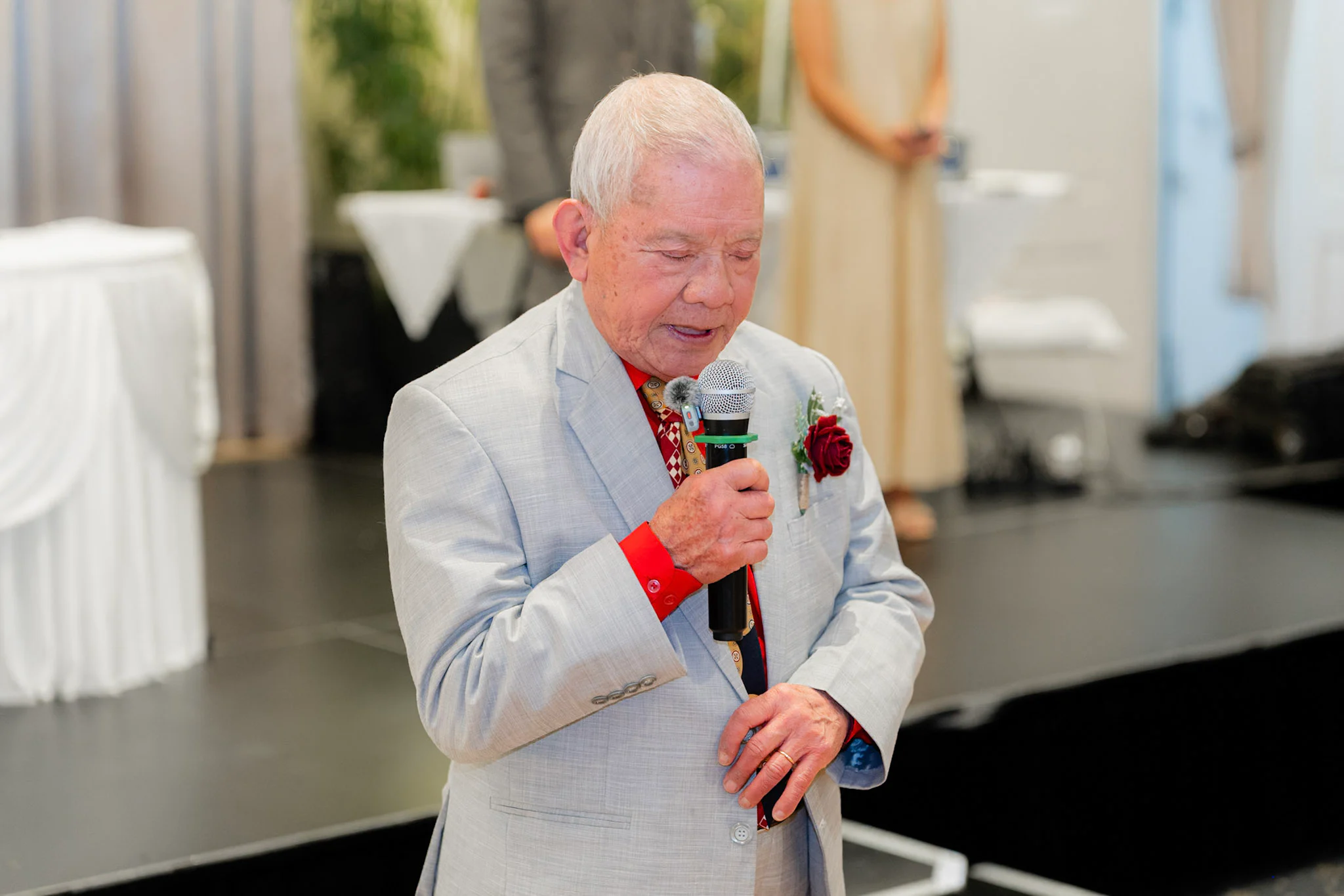 A wedding guest smiling as he gives a reception speech