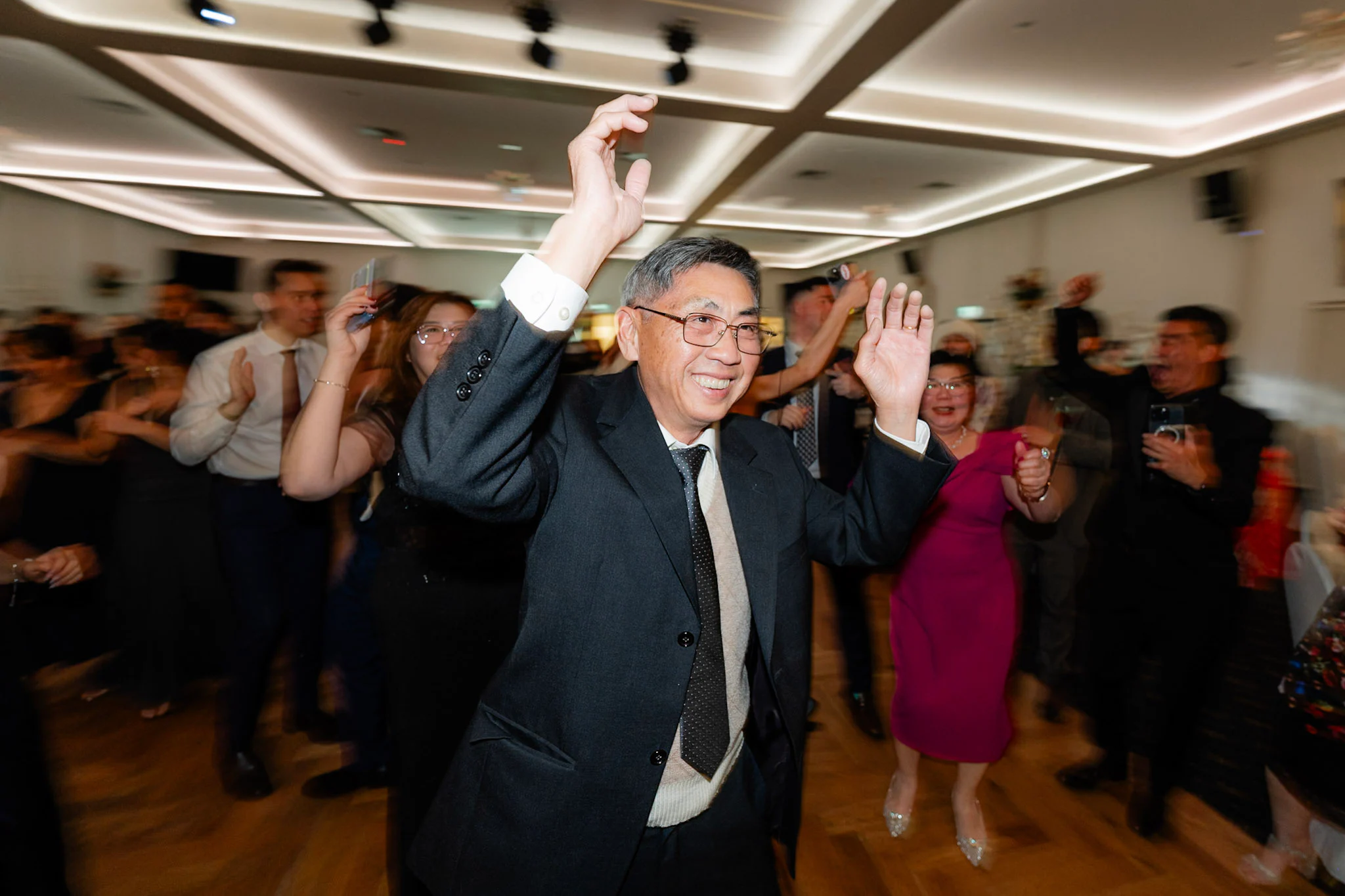 A wedding guest dancing with both hands in the air