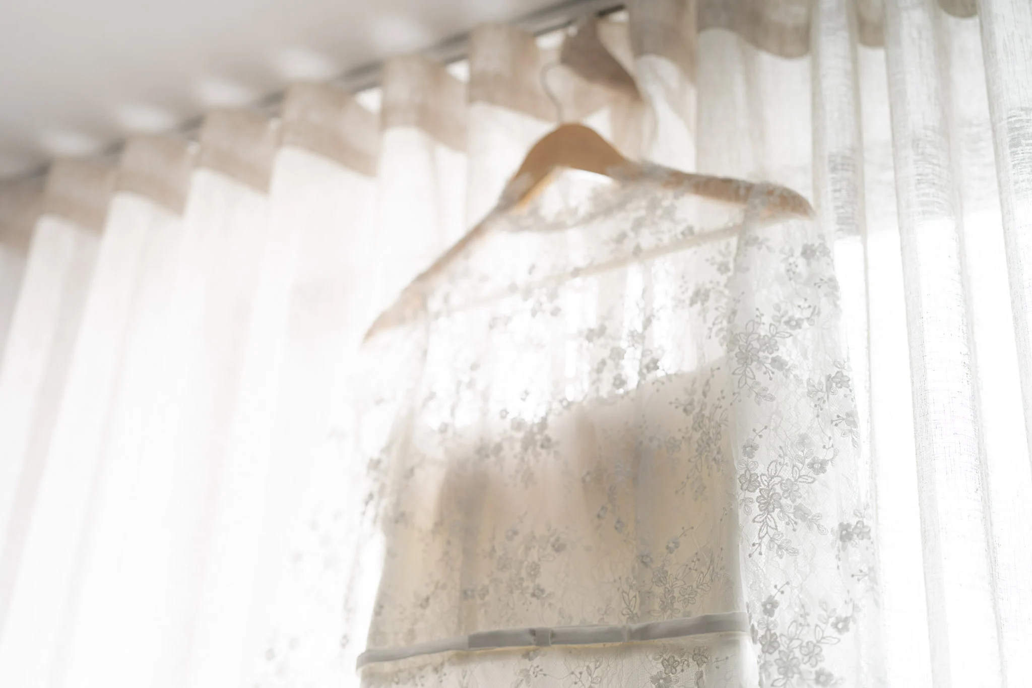 Joy's wedding dress hanging in soft window light