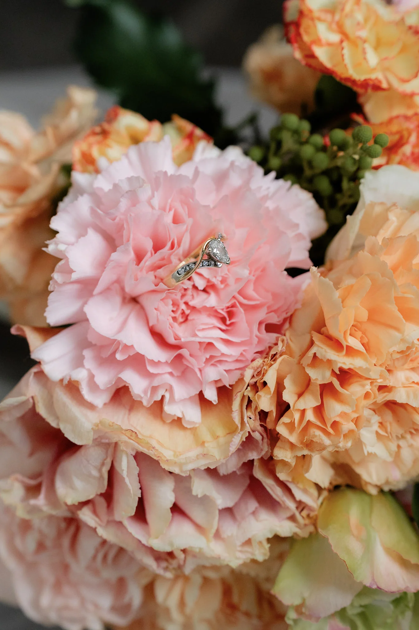 A wedding ring nestled among the pink bouquet flowers