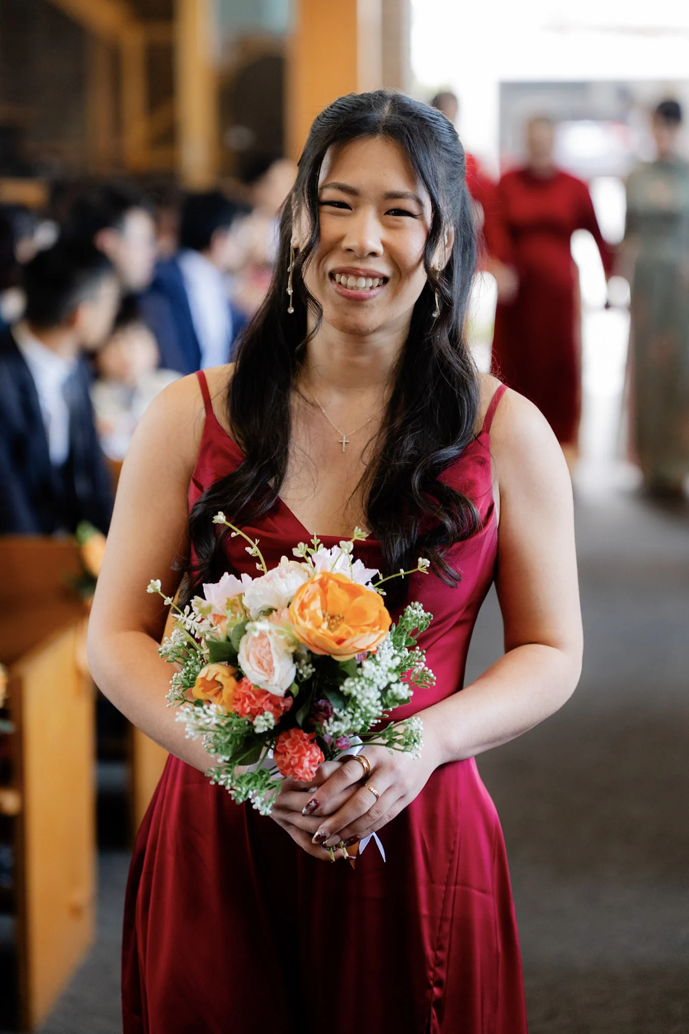 A bridesmaid smiling as she walks down the church aisle