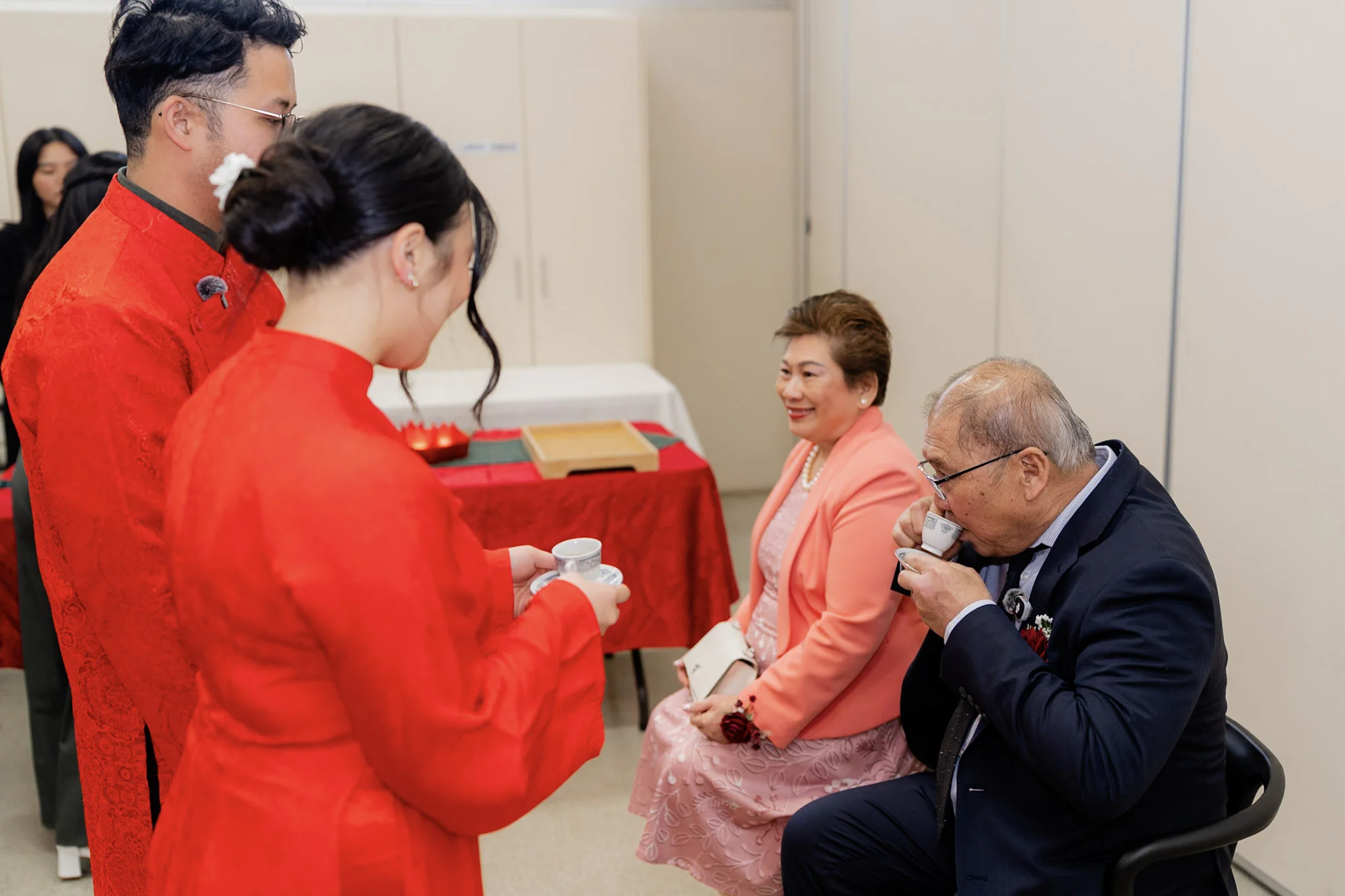 A family elder smiling as Ron and Joy serve tea