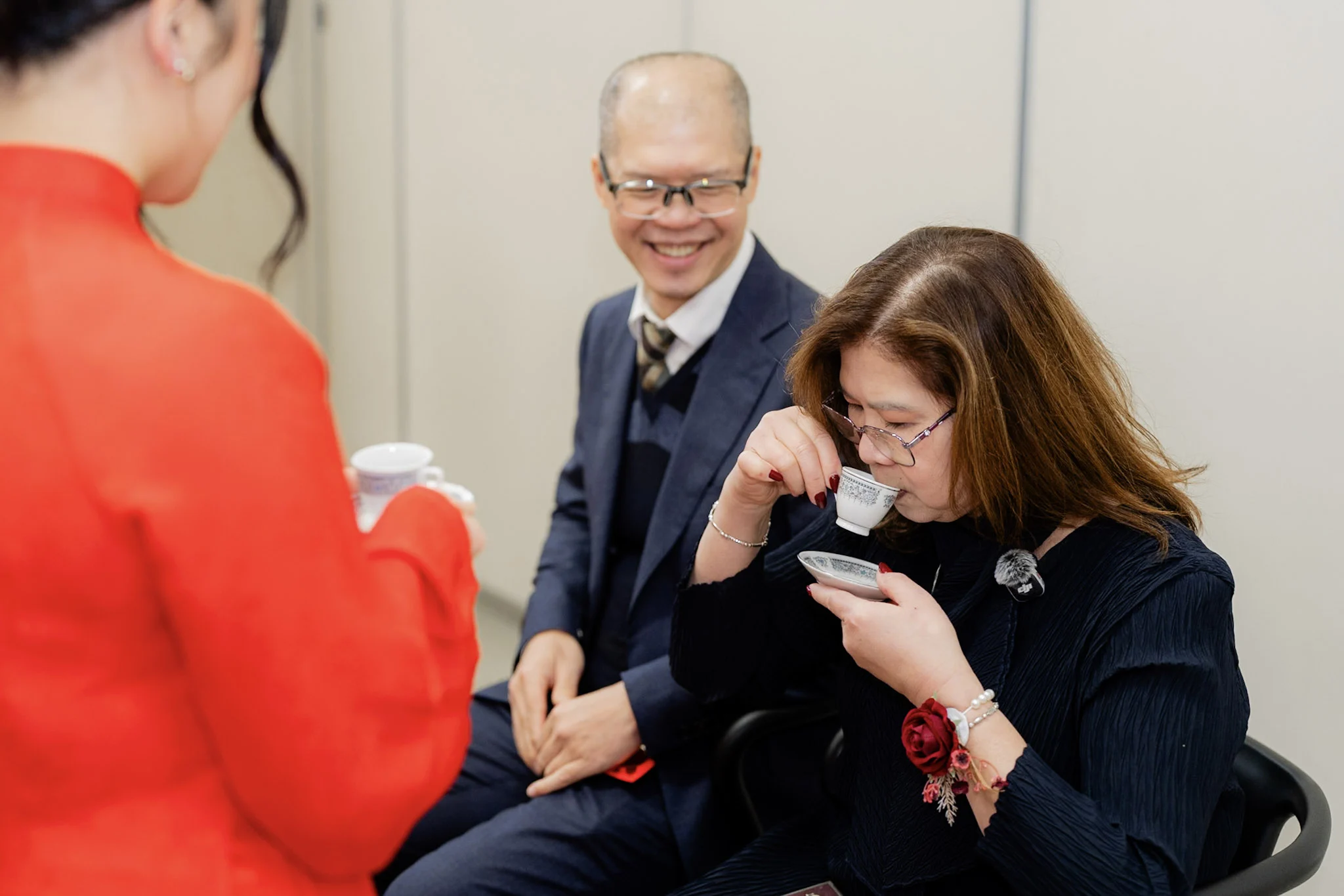 A family elder enjoying tea while her companion smiles
