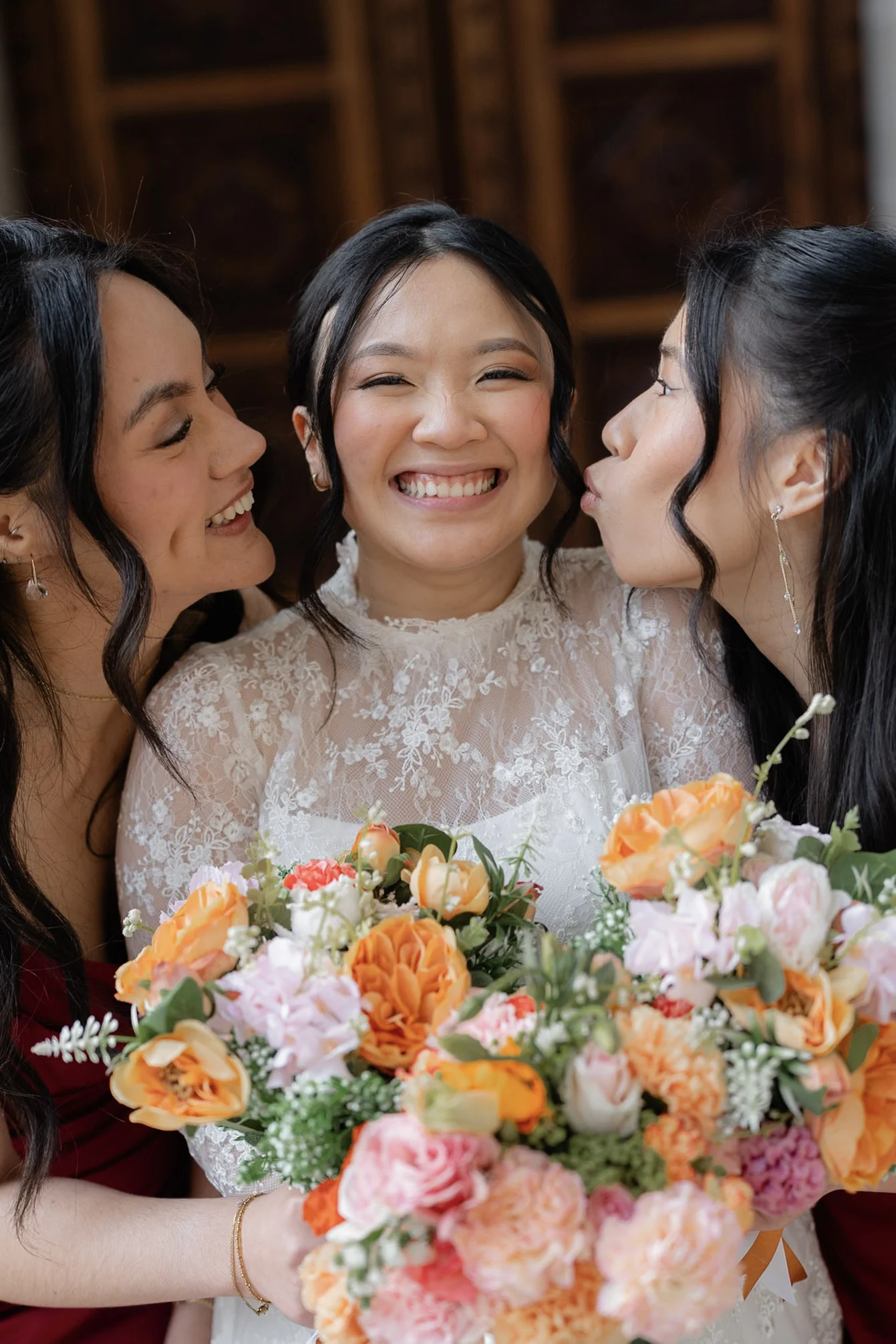 Joy laughing as her bridesmaids kiss her cheeks