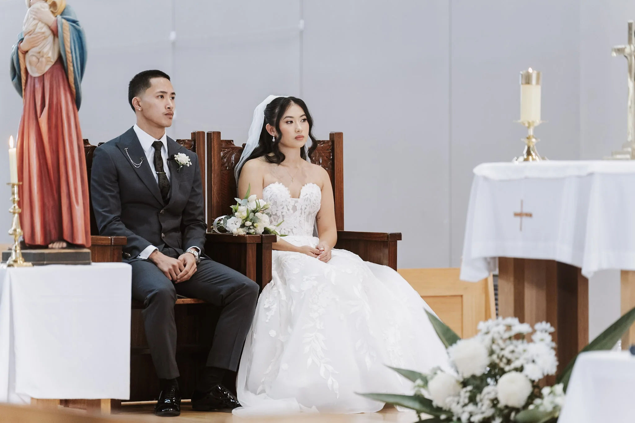 Kevin and Tee seated together beside the altar flowers