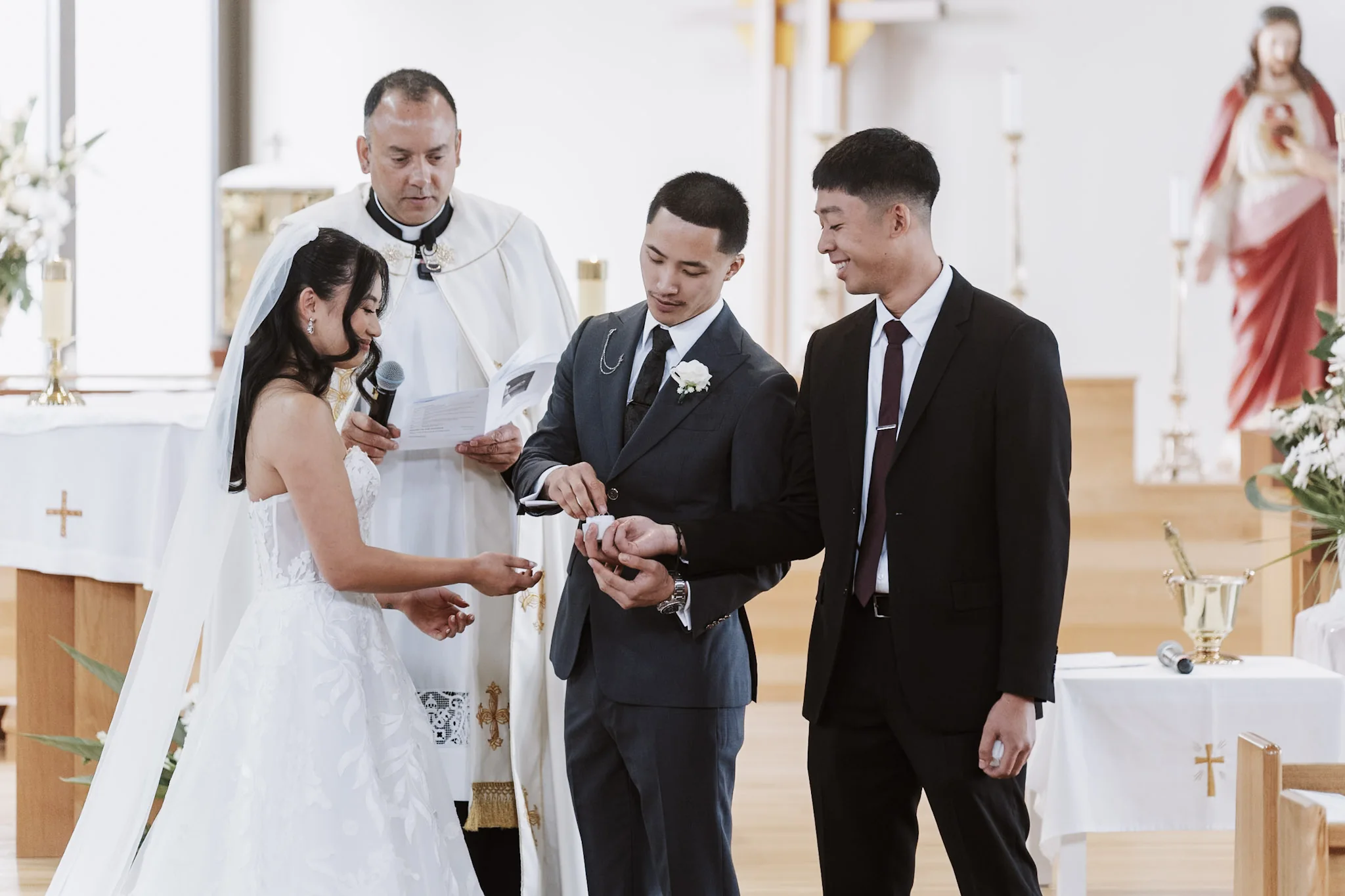 Kevin and Tee exchanging rings with their wedding party beside them