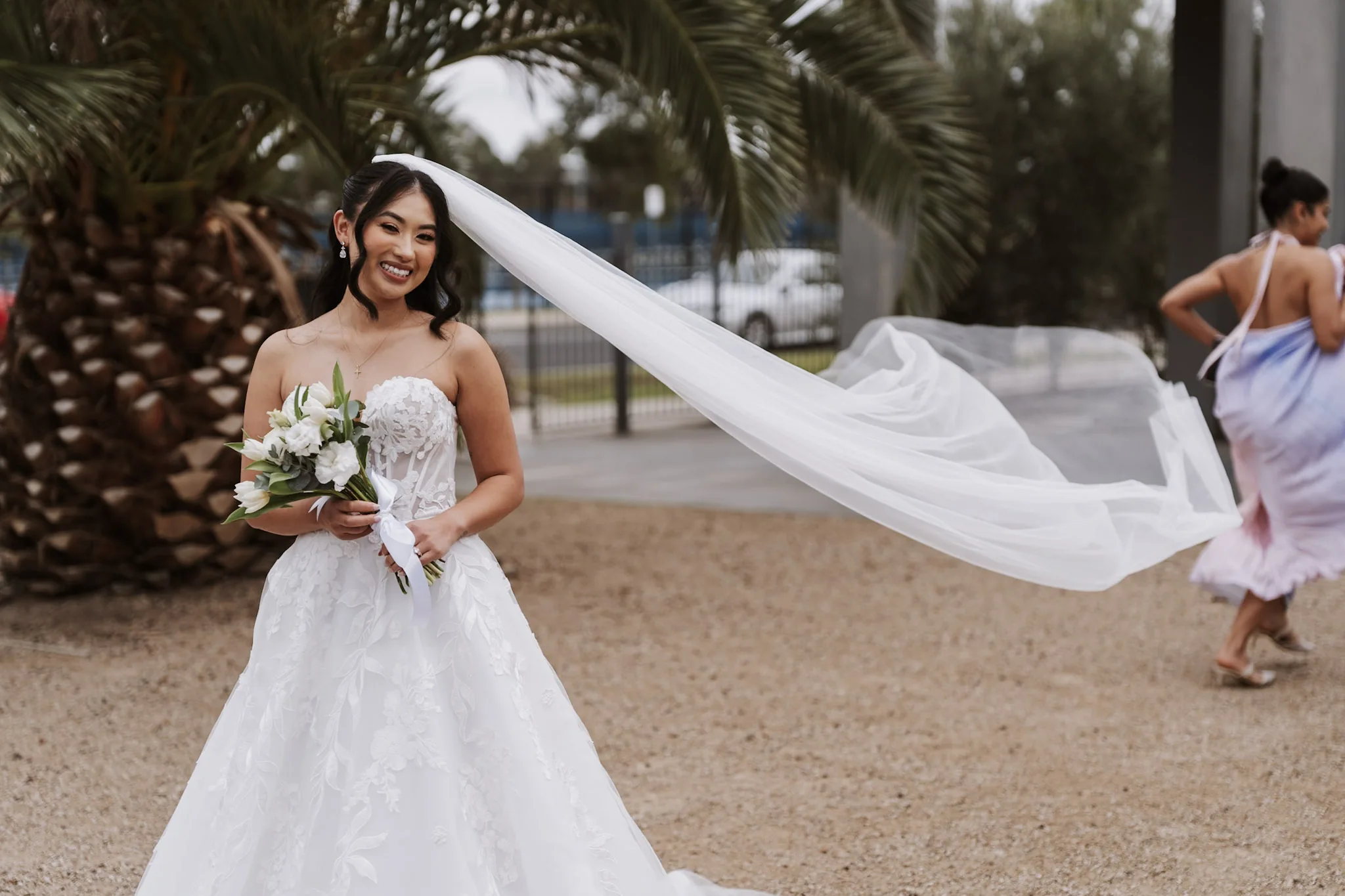 Tee laughing as a friend lifts her veil into the breeze