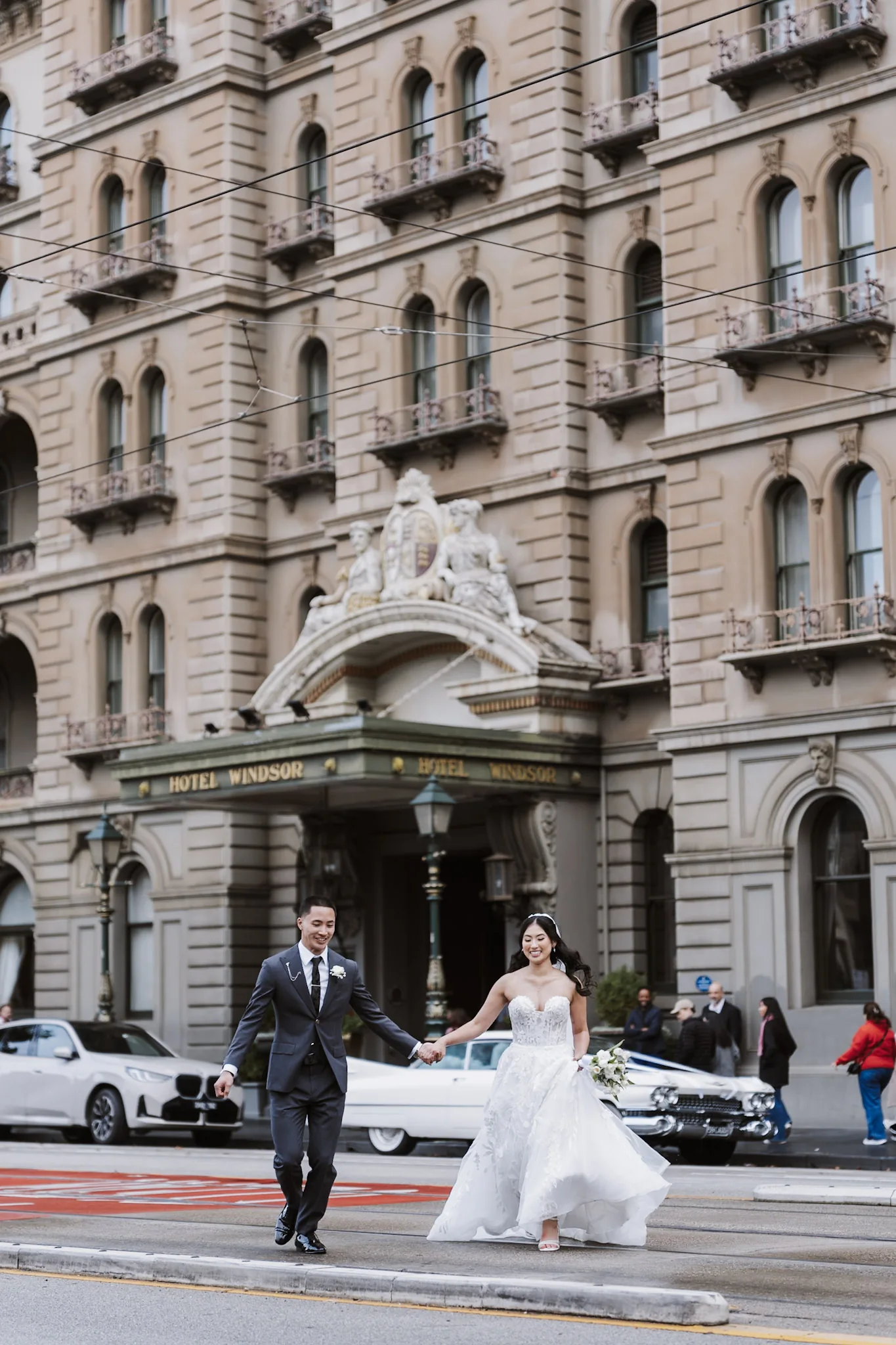 Kevin and Tee walking across a Melbourne street beside historic architecture