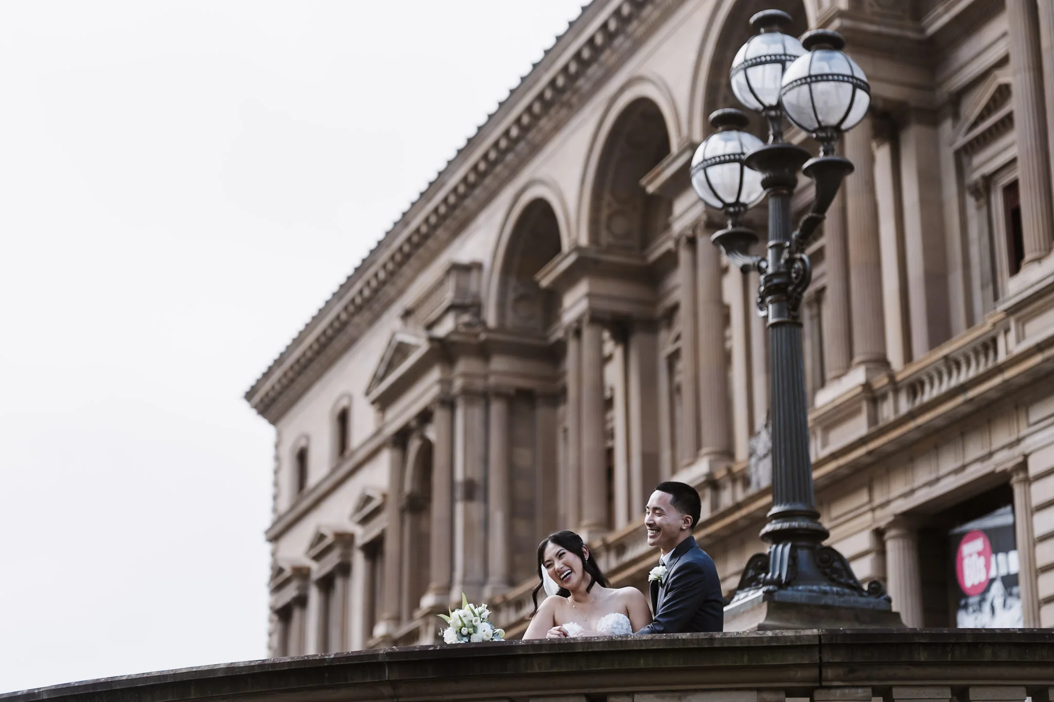 An architectural view of Kevin and Tee above a stone balustrade