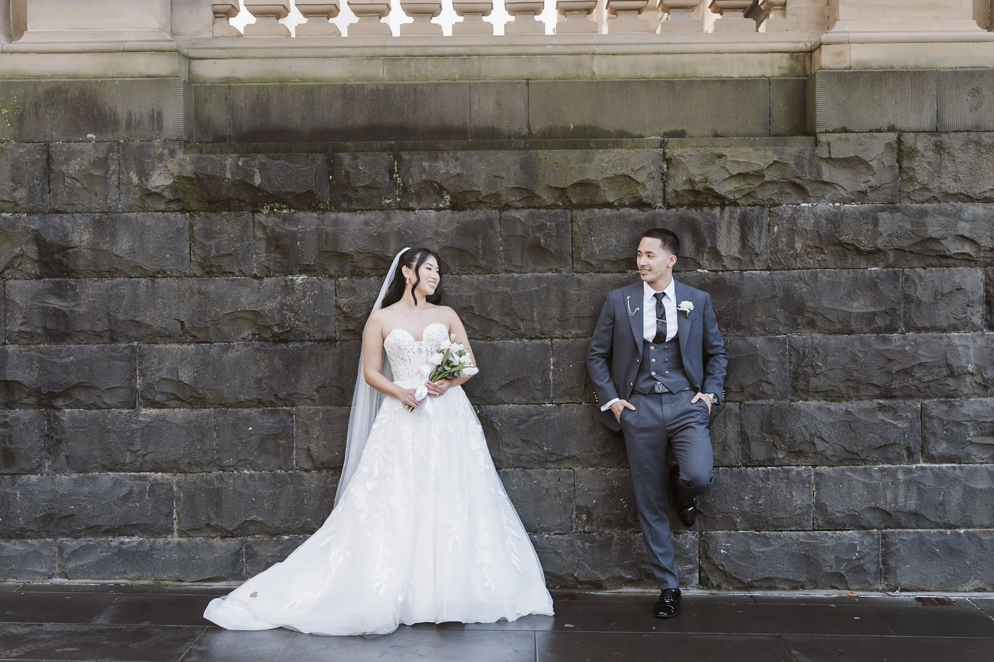 Kevin and Tee sharing a relaxed moment against a bluestone wall